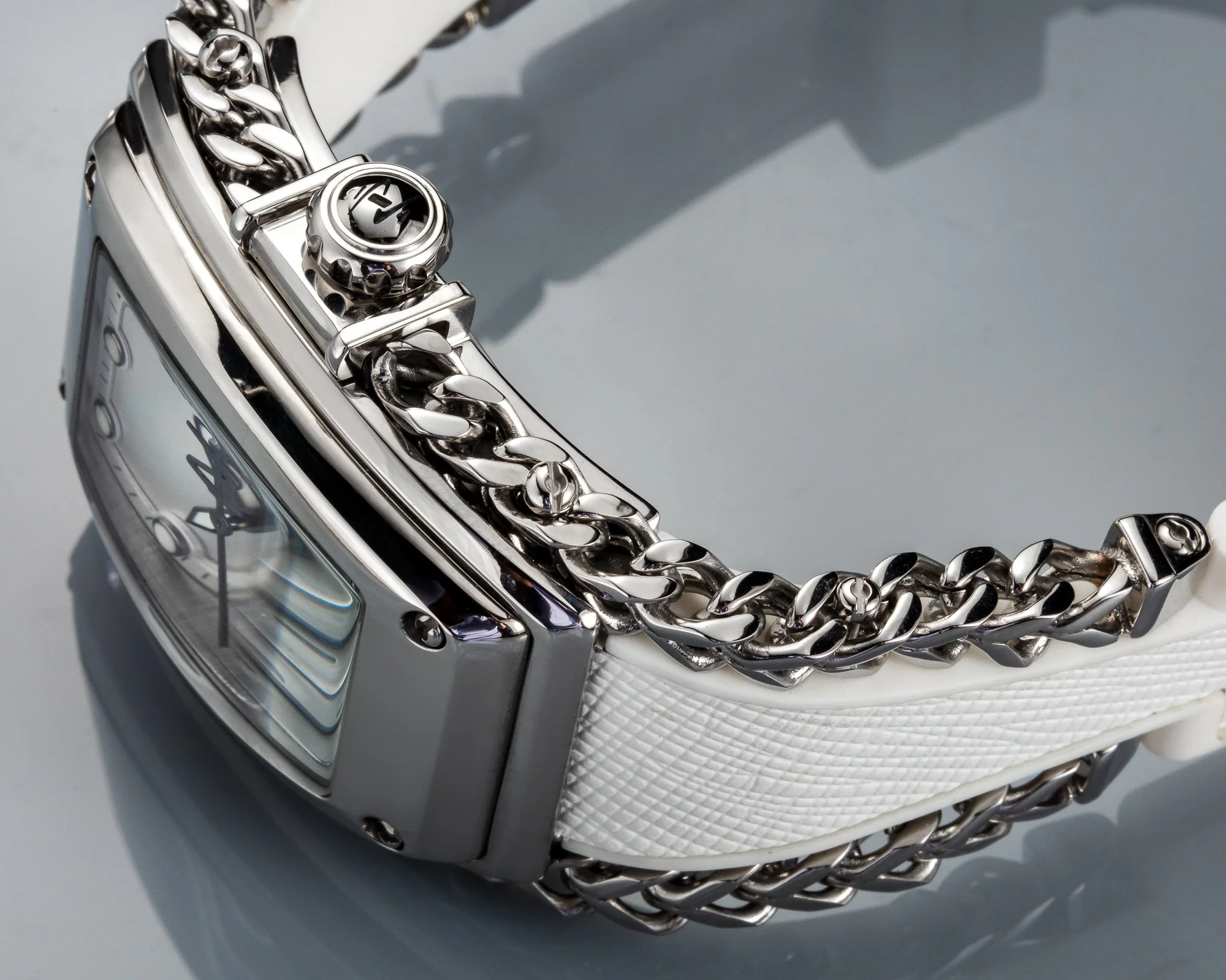 Close-up of a silver wristwatch with a white band, featuring a silver chain bracelet.