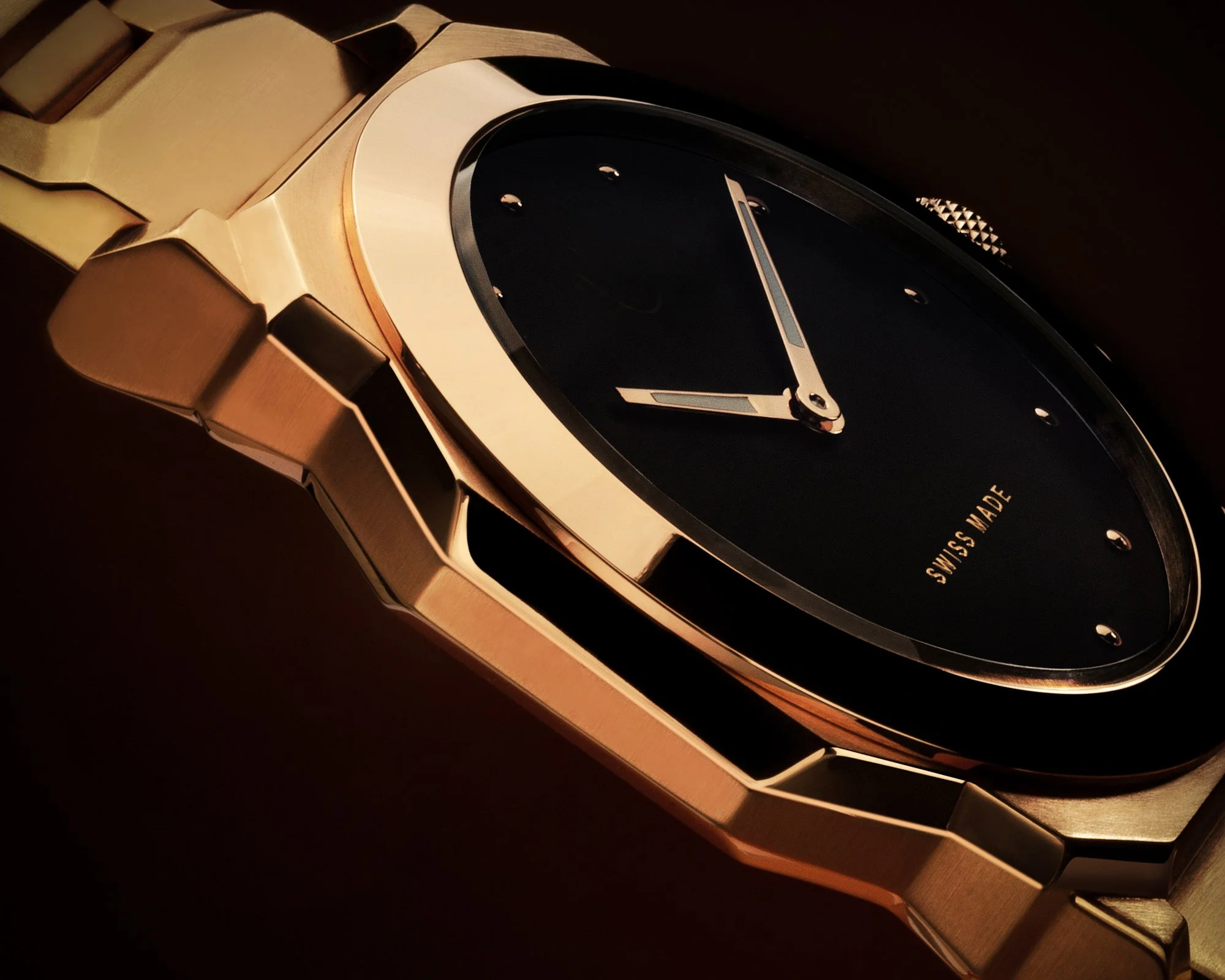 Close-up of a luxury wristwatch with a gold-colored band and a black watch face, showing part of the band, bezel, and watch face.