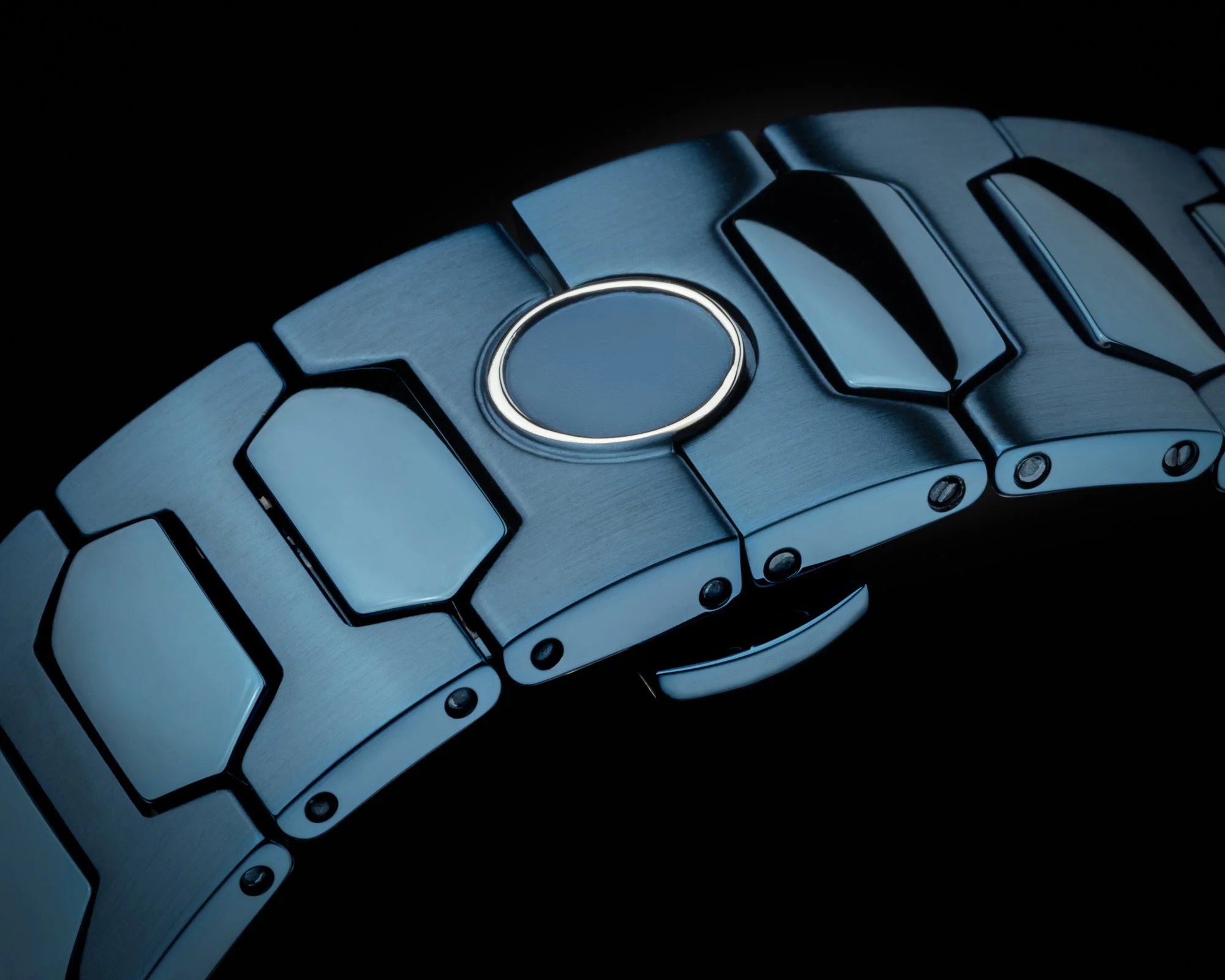 Close-up of a metallic smartwatch band with a circular button, set against a black background.