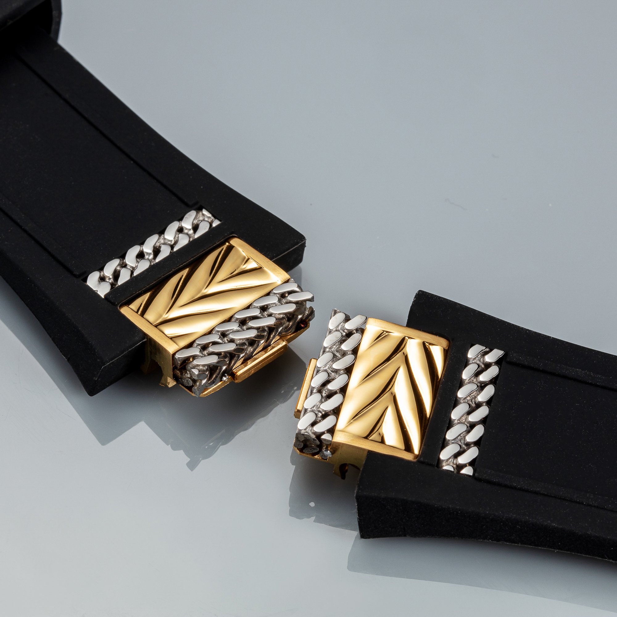 Close-up of a black jewelry box containing gold and silver jewelry with chain links and a decorative gold piece.