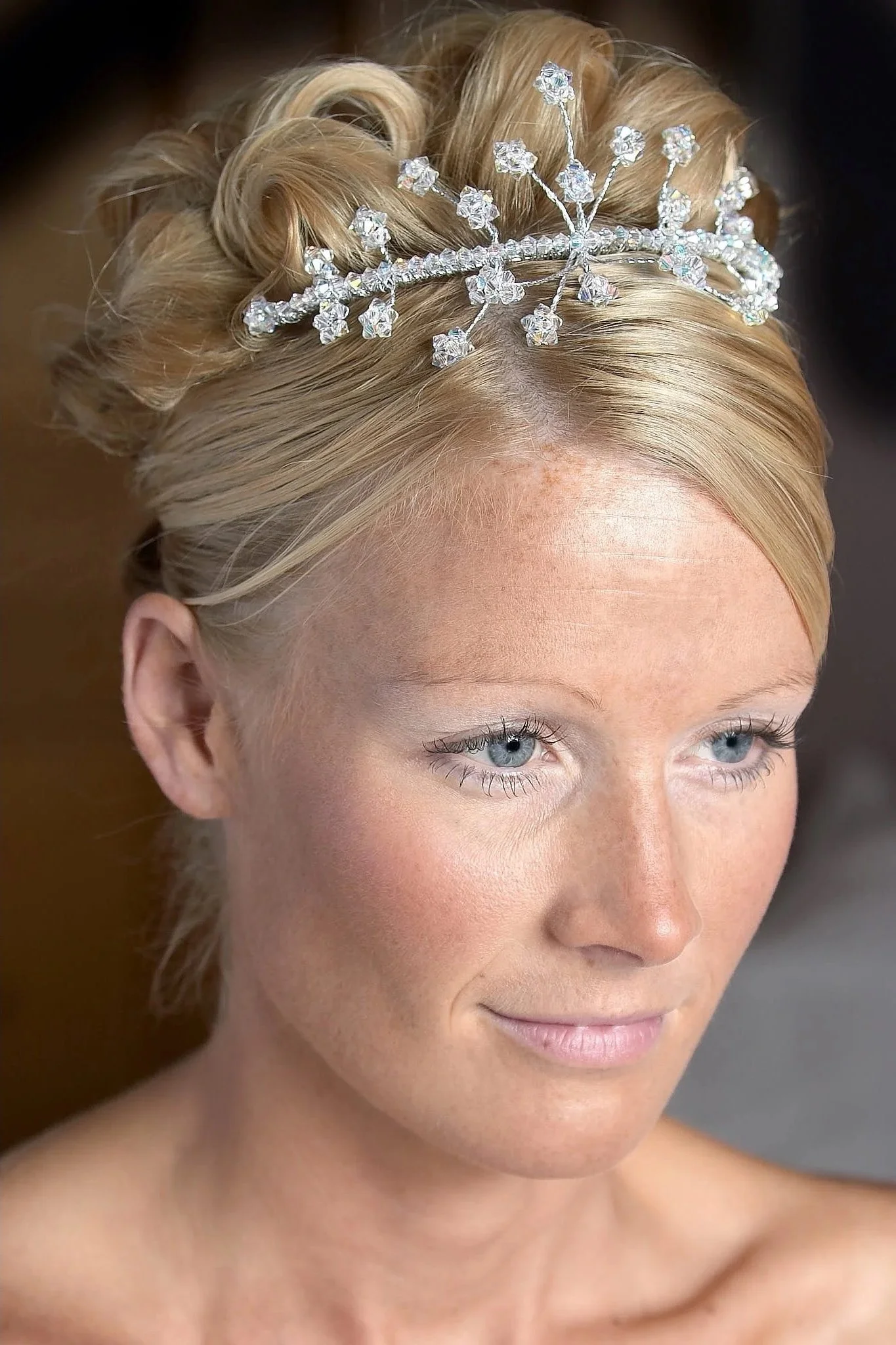 Close-up of a woman with styled blonde hair wearing a snowflake-shaped diamond tiara.
