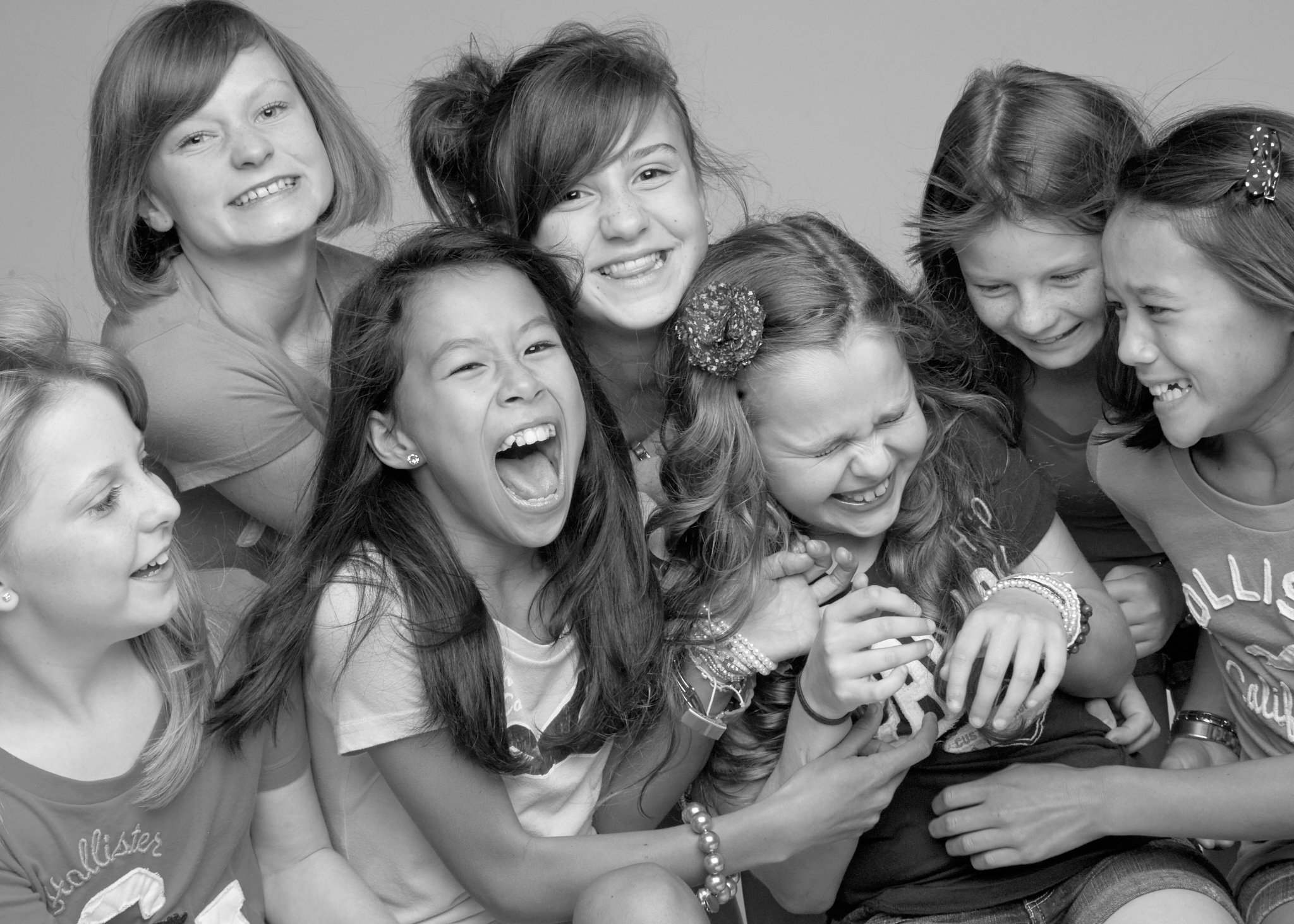 Group of girls smiling and laughing together, some with their eyes closed, in a friendly, joyful moment.