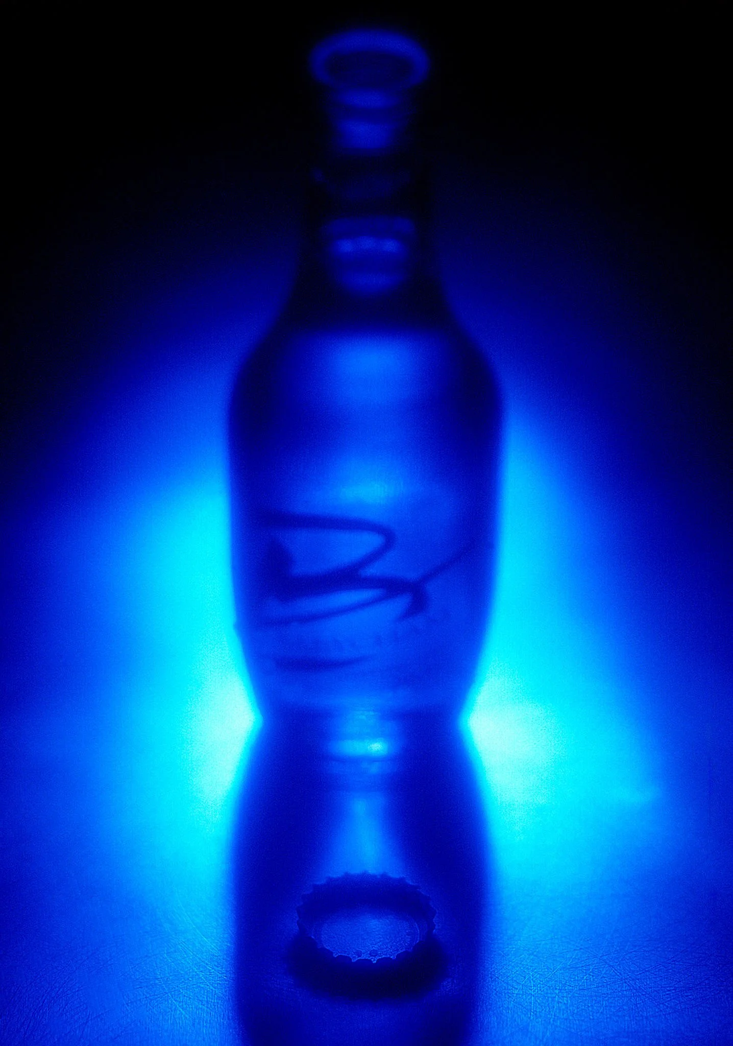 A glass lightbulb with a visible filament inside, illuminated with blue light, placed on a reflective surface with blue lighting in the background.
