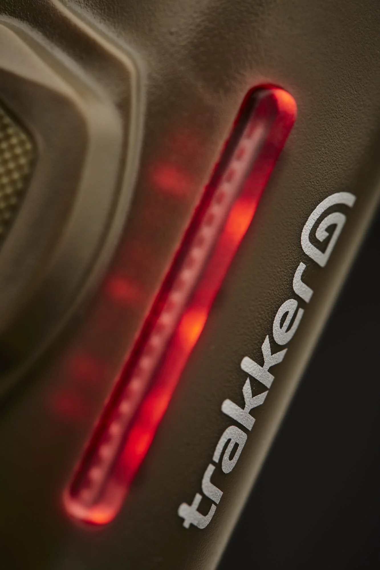 Close-up of a metallic device with a red glowing indicator light on the side, and partially visible white text.