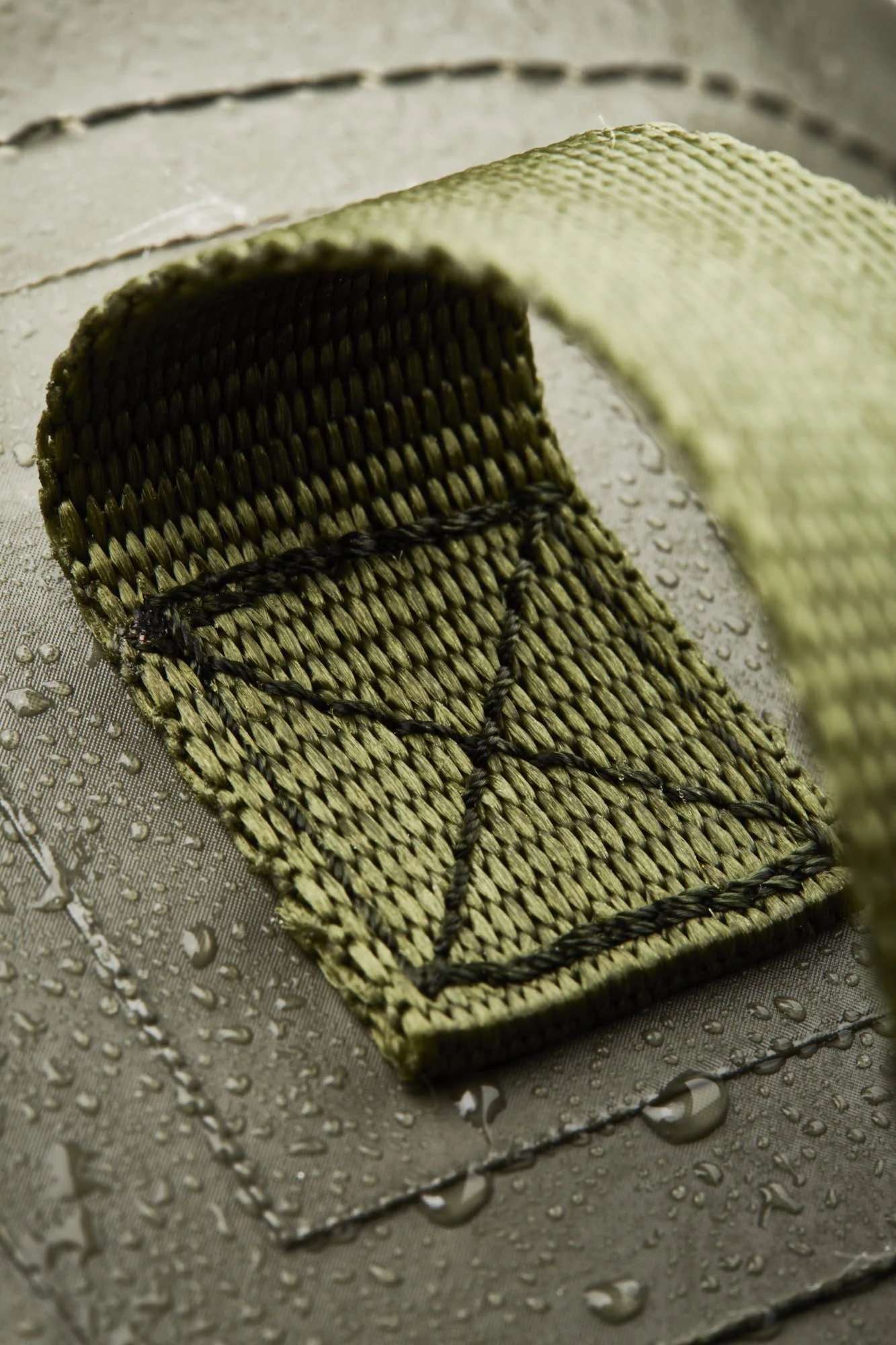 A woven basket with a curved top edge on a wet, metallic surface with water droplets.