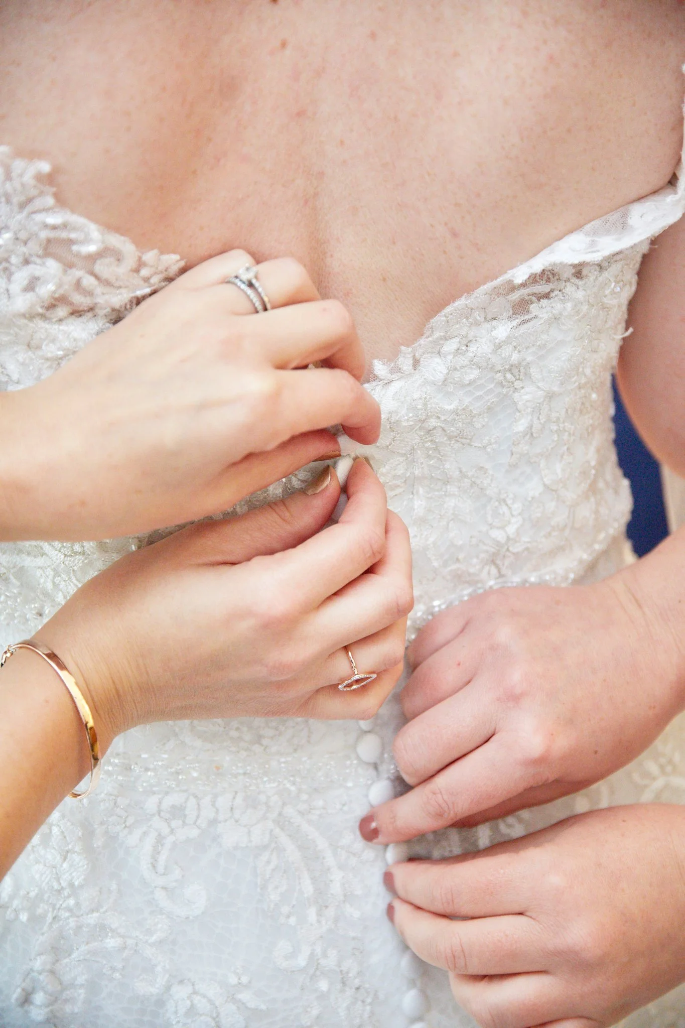 Close-up of hands adjusting a lace wedding dress on a bride.