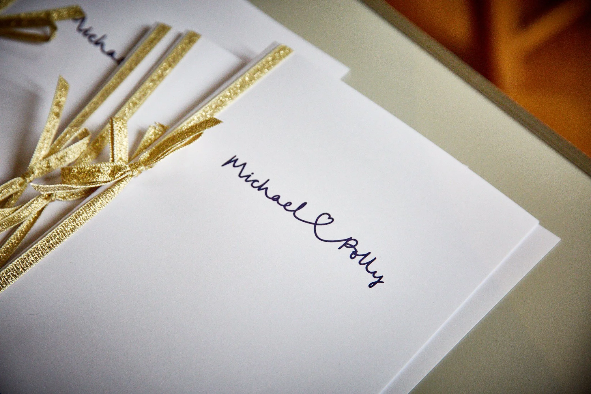 Close-up of a white greeting card with gold ribbon accents and handwritten message that says "Wishing you".