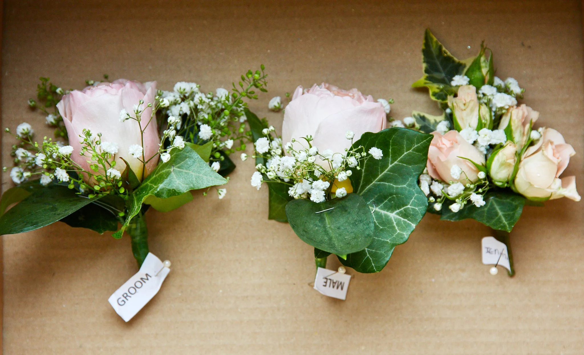 Two floral arrangements with pink roses, white baby's breath, and green leafy accents on a beige background.