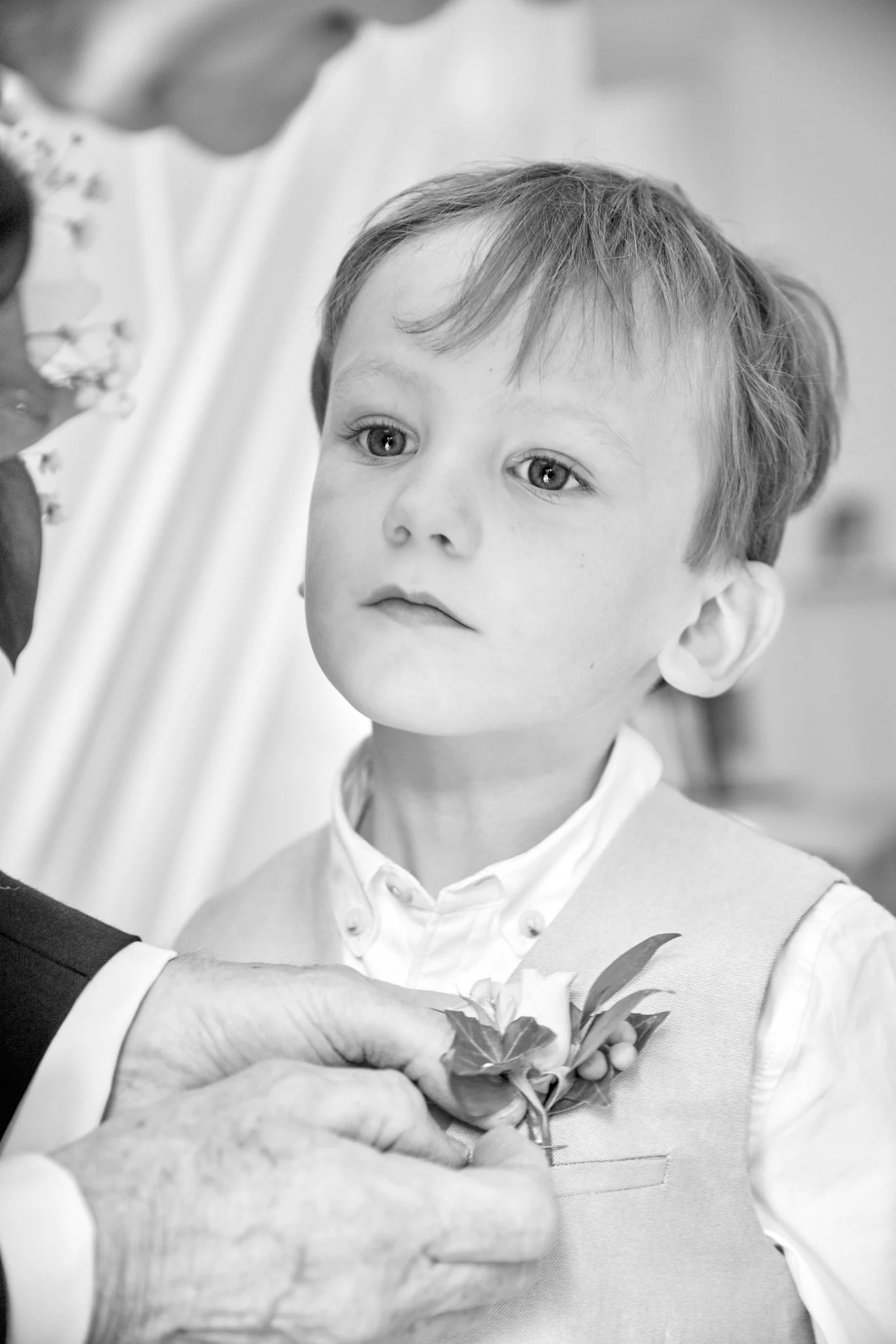 A young boy in a school vest is receiving a flower from an adult during a presentation or ceremony.