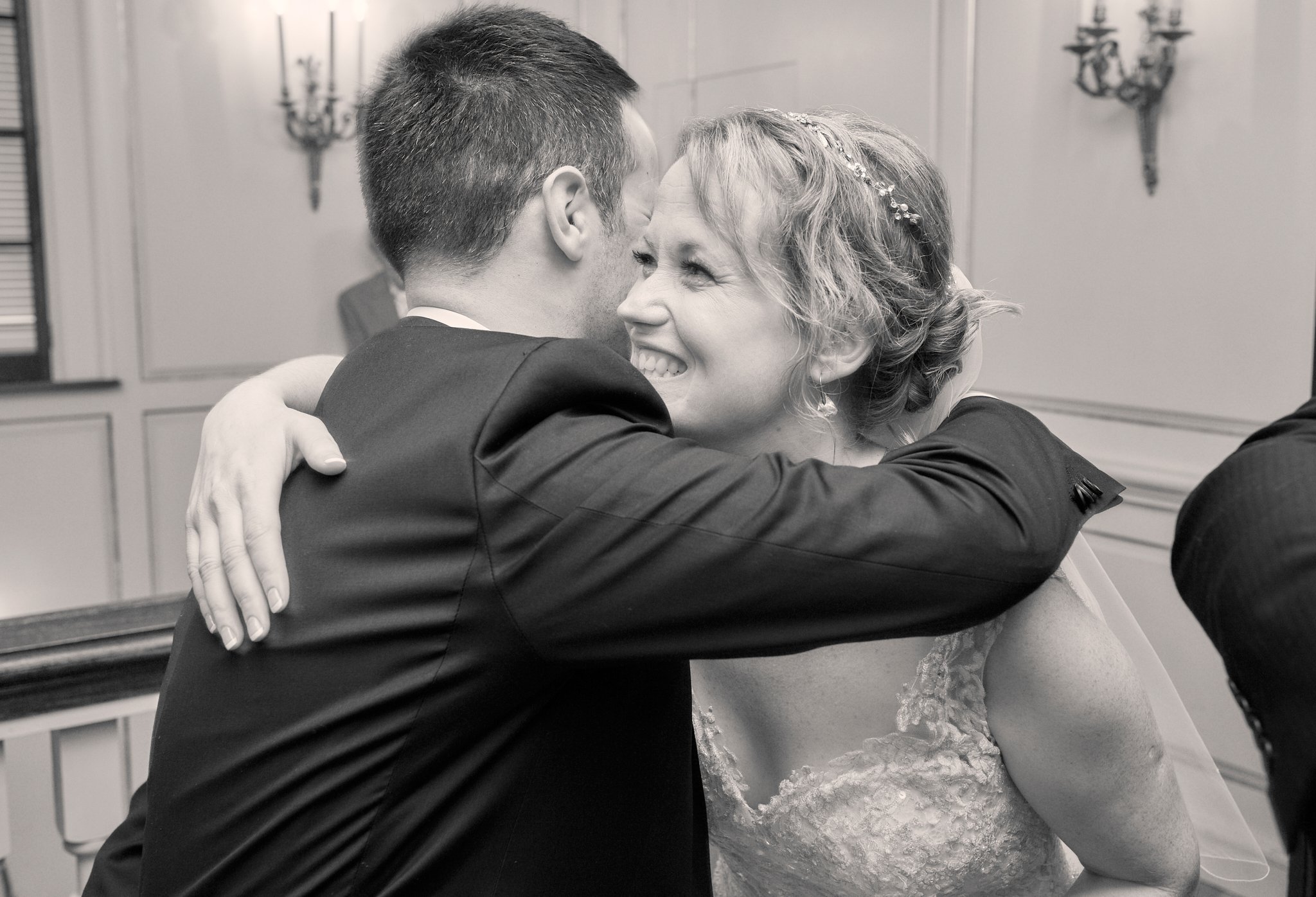 A couple is dancing closely, smiling and embracing each other during their wedding celebration in a decorated room.