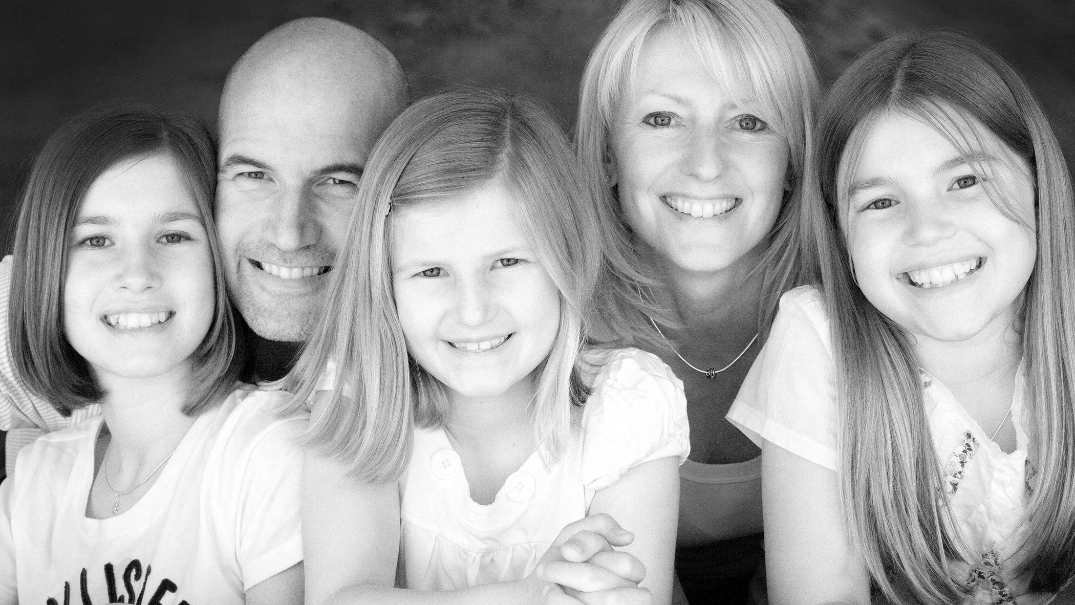 Group portrait of three adult women and three young girls, all smiling, in black and white.