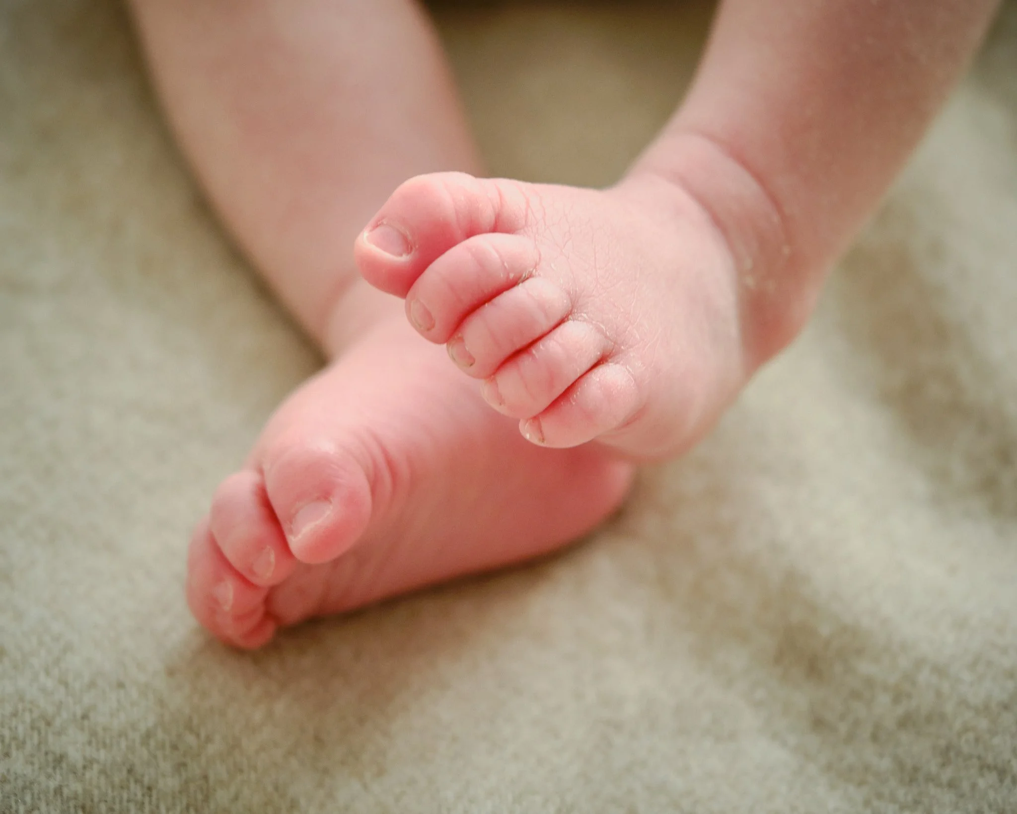 Close-up of a baby's feet and legs, with the baby lying on a soft surface.