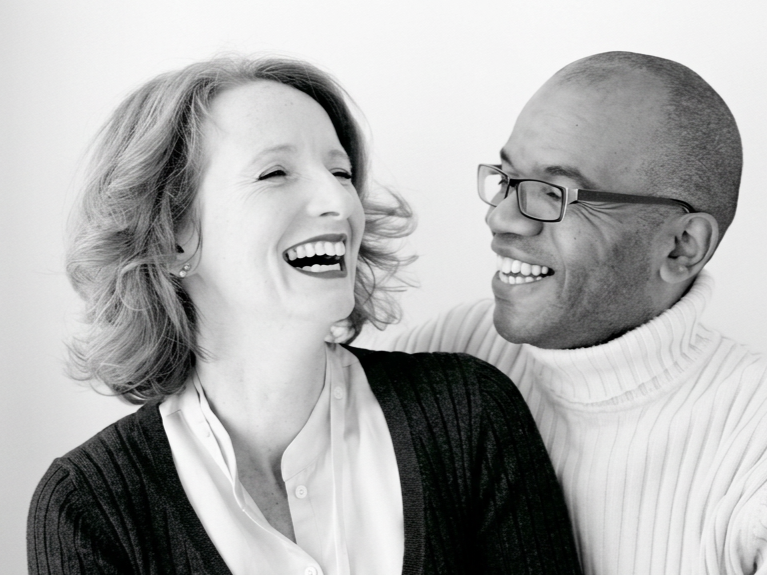 A black-and-white photo of a woman and a man smiling and laughing together.