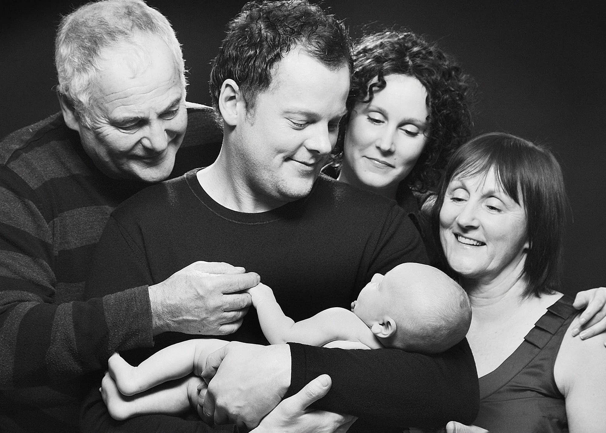 A group of five people, including three women and two men, are hugging and smiling, sharing a joyful moment together.