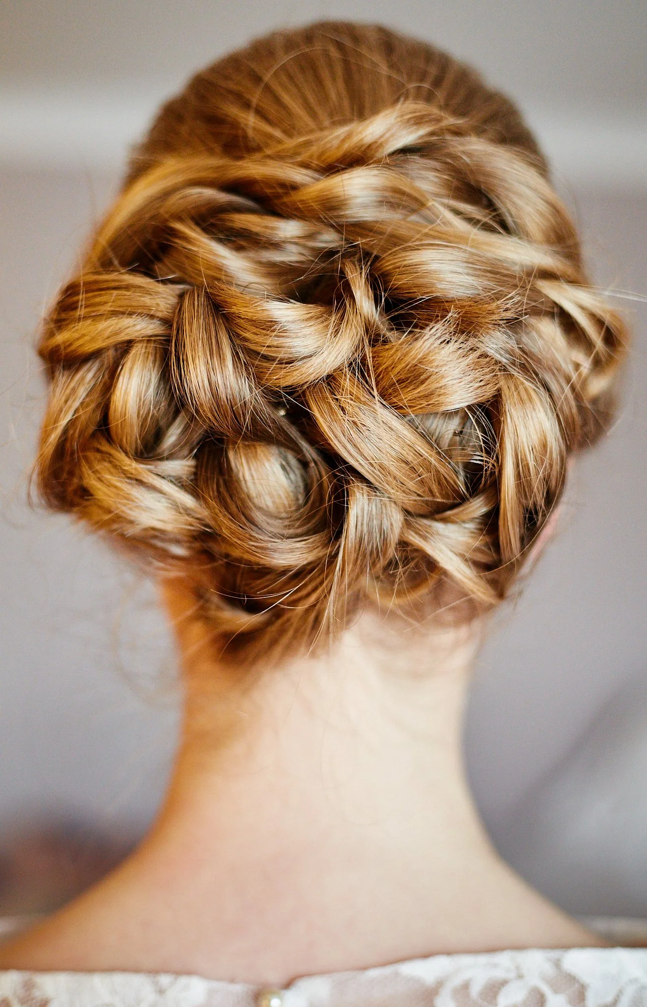 Back of a woman's head with blonde hair styled in an intricate braid.