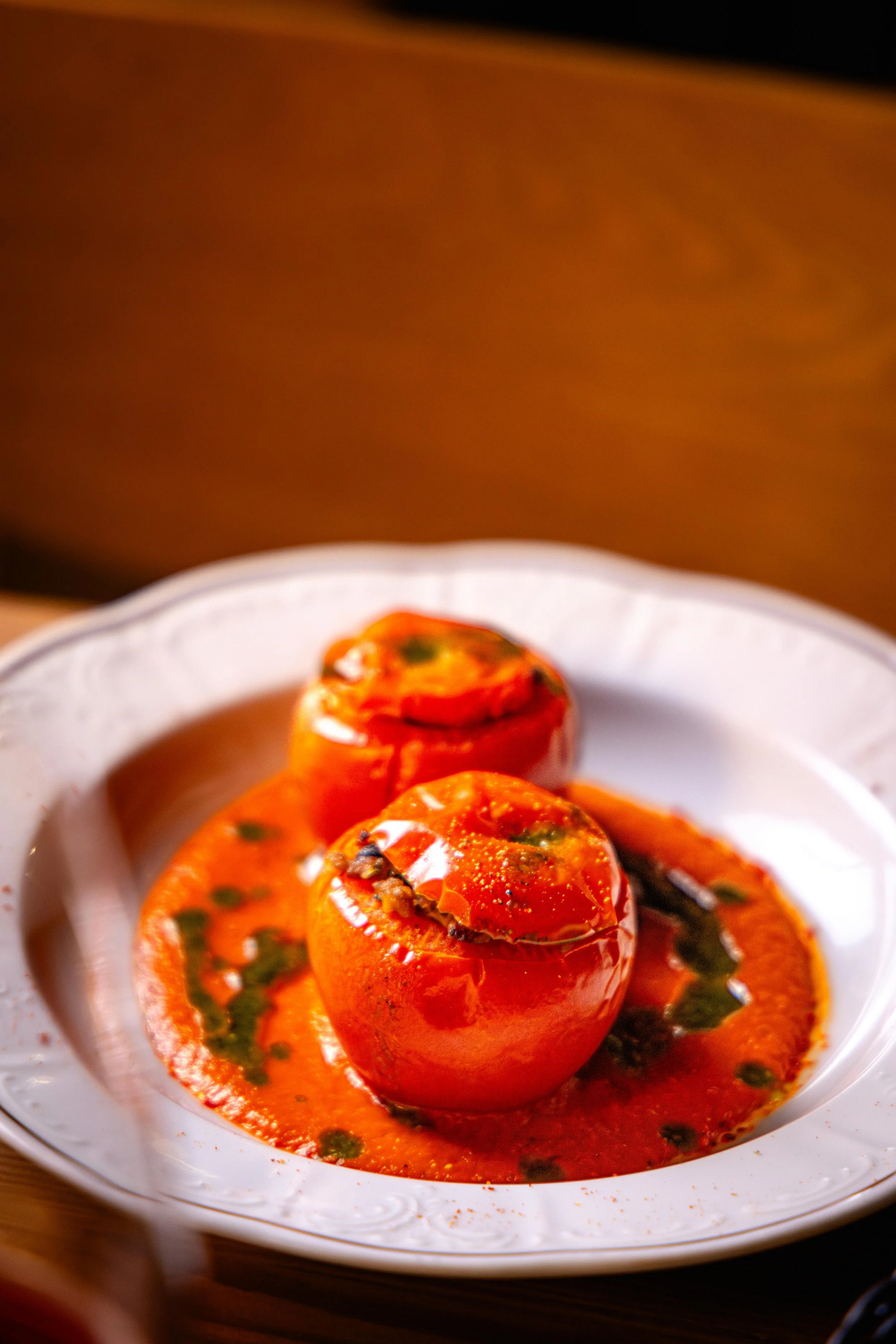 Tomates farcis dans une sauce épicée, garnis d'herbes, servis dans un bol blanc.