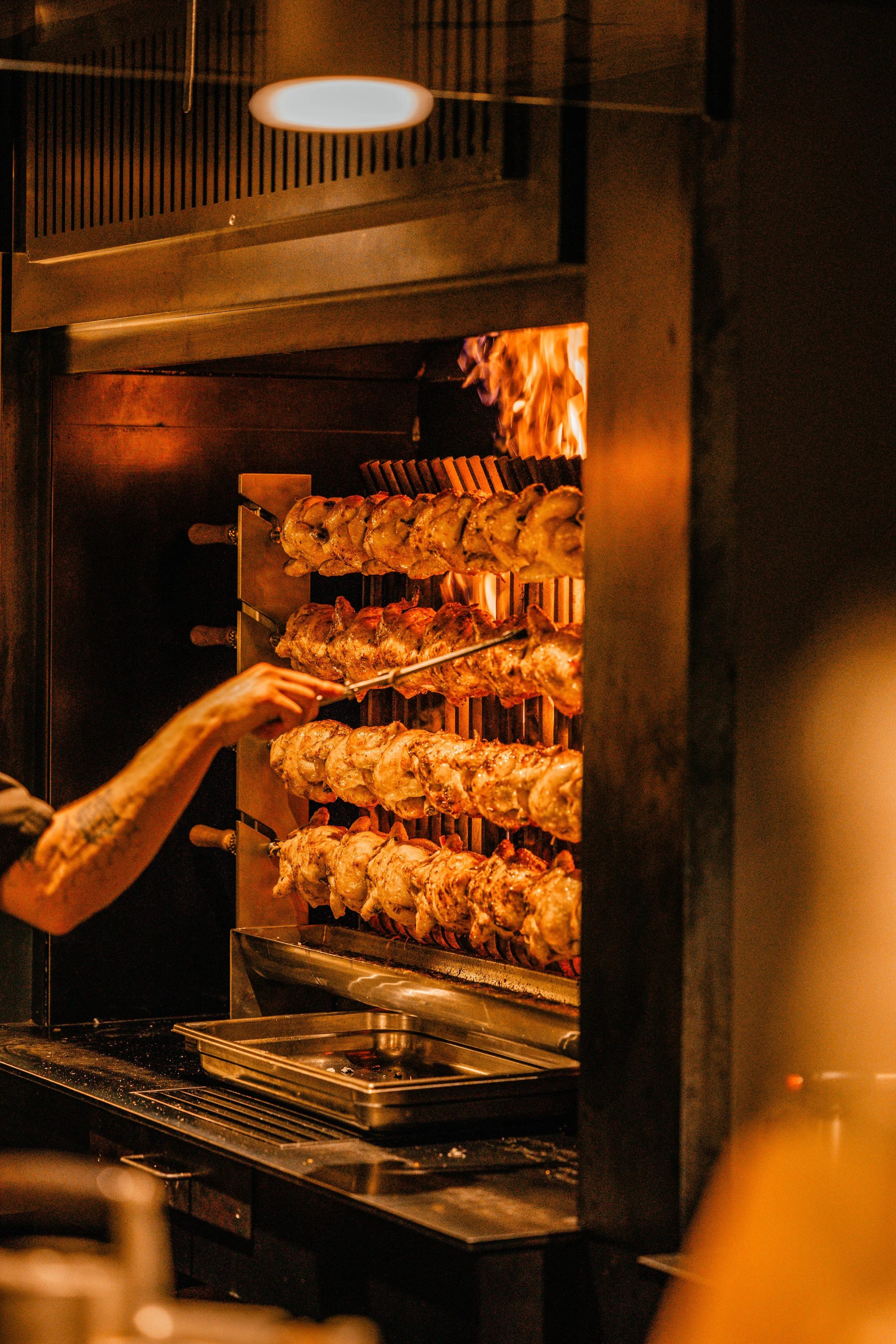 Des brochettes de poulet grillées en train de cuire dans un four à brochettes.