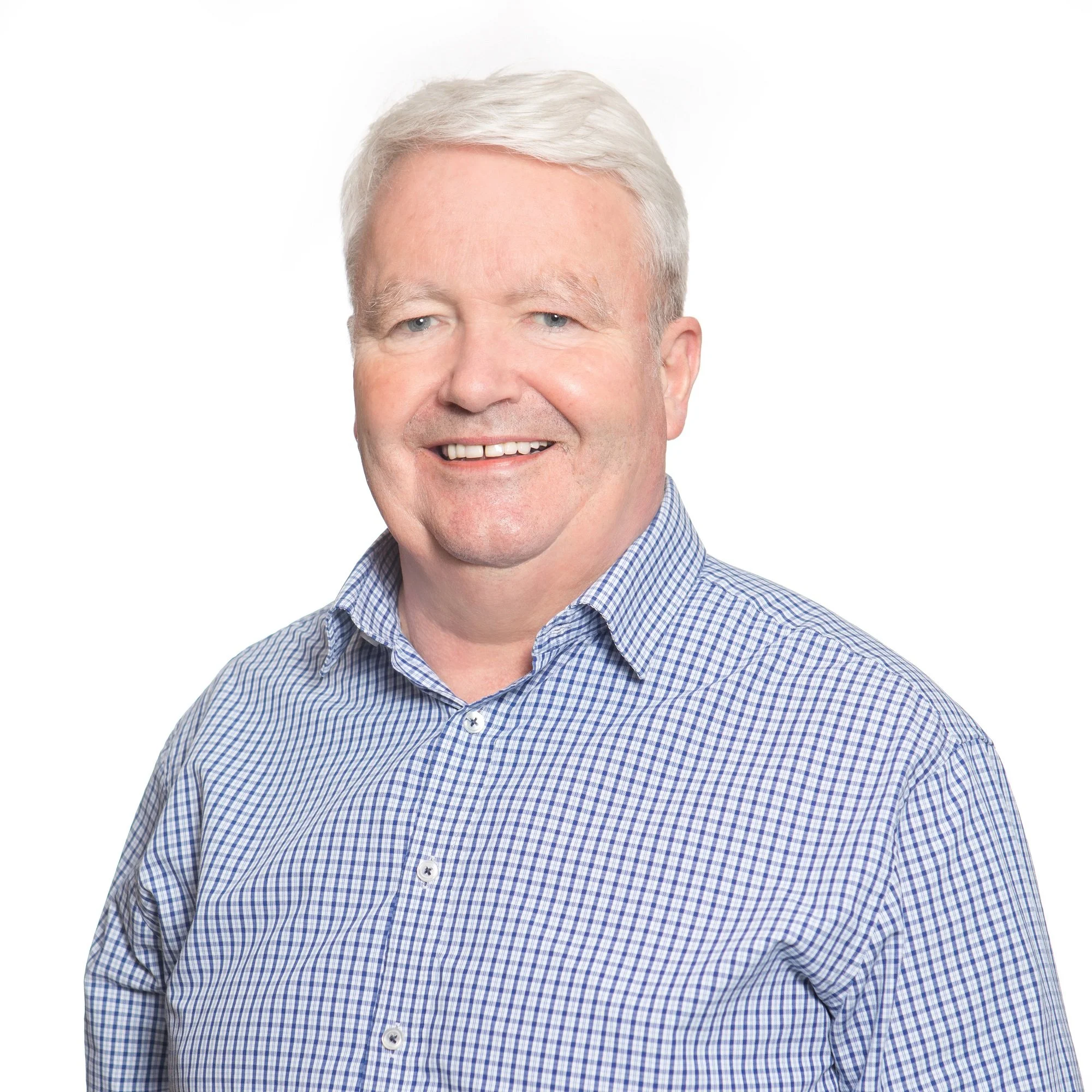 Close-up of a smiling middle-aged man with gray hair and blue eyes, wearing a blue checkered shirt, against a white background.