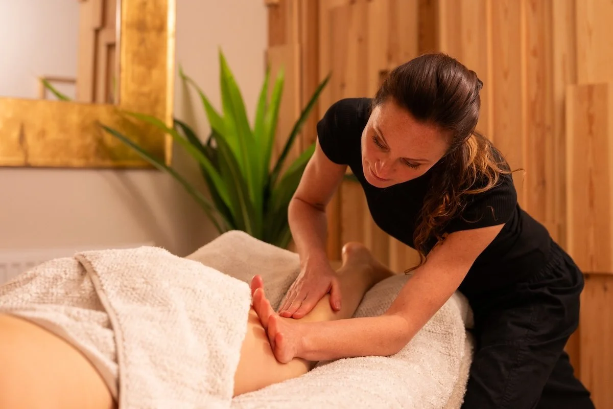 Virginie providing a deep tissue massage treatment using forearm pressure.