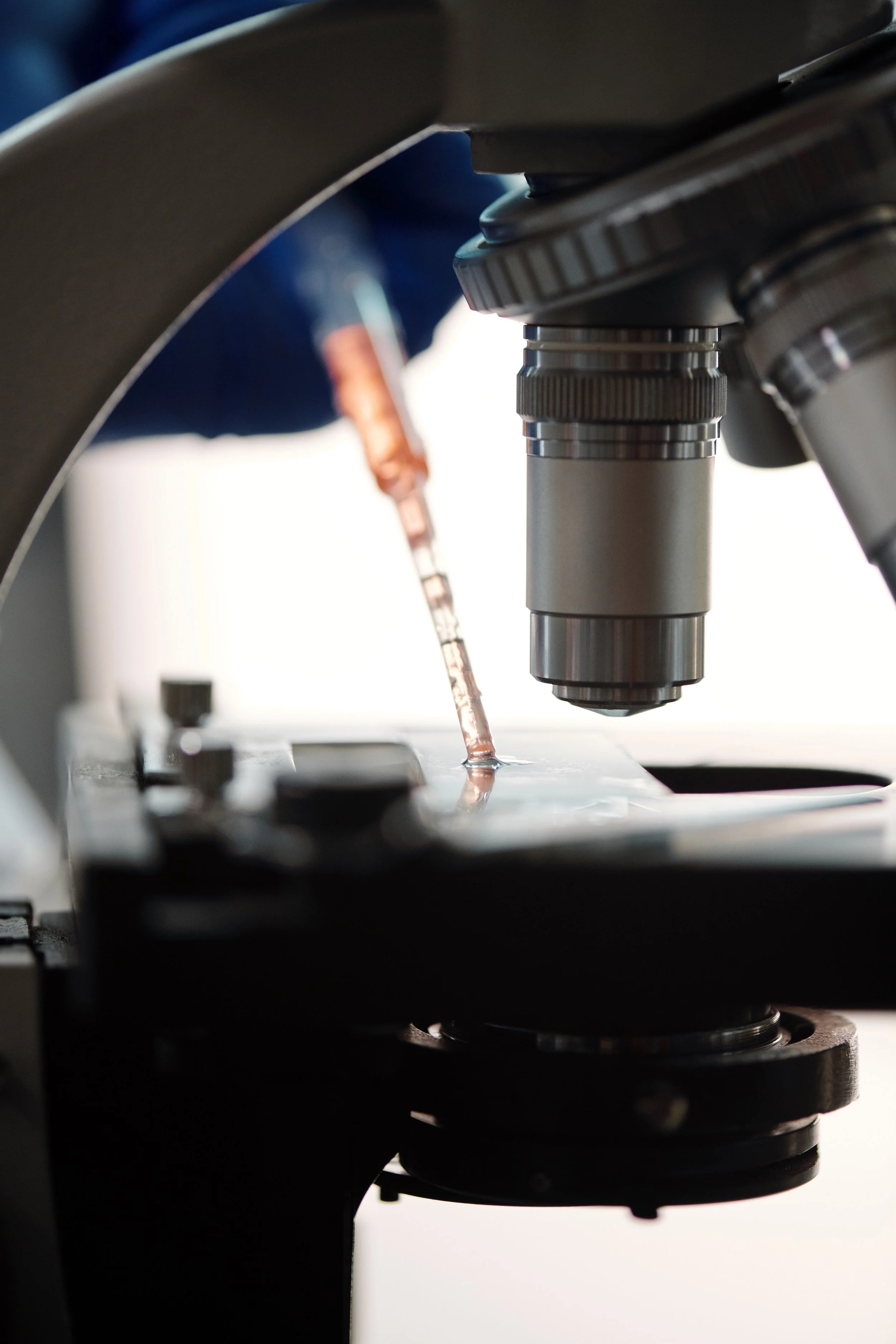Close-up view of a microscope focusing on a glass slide holding a specimen for scientific examination.