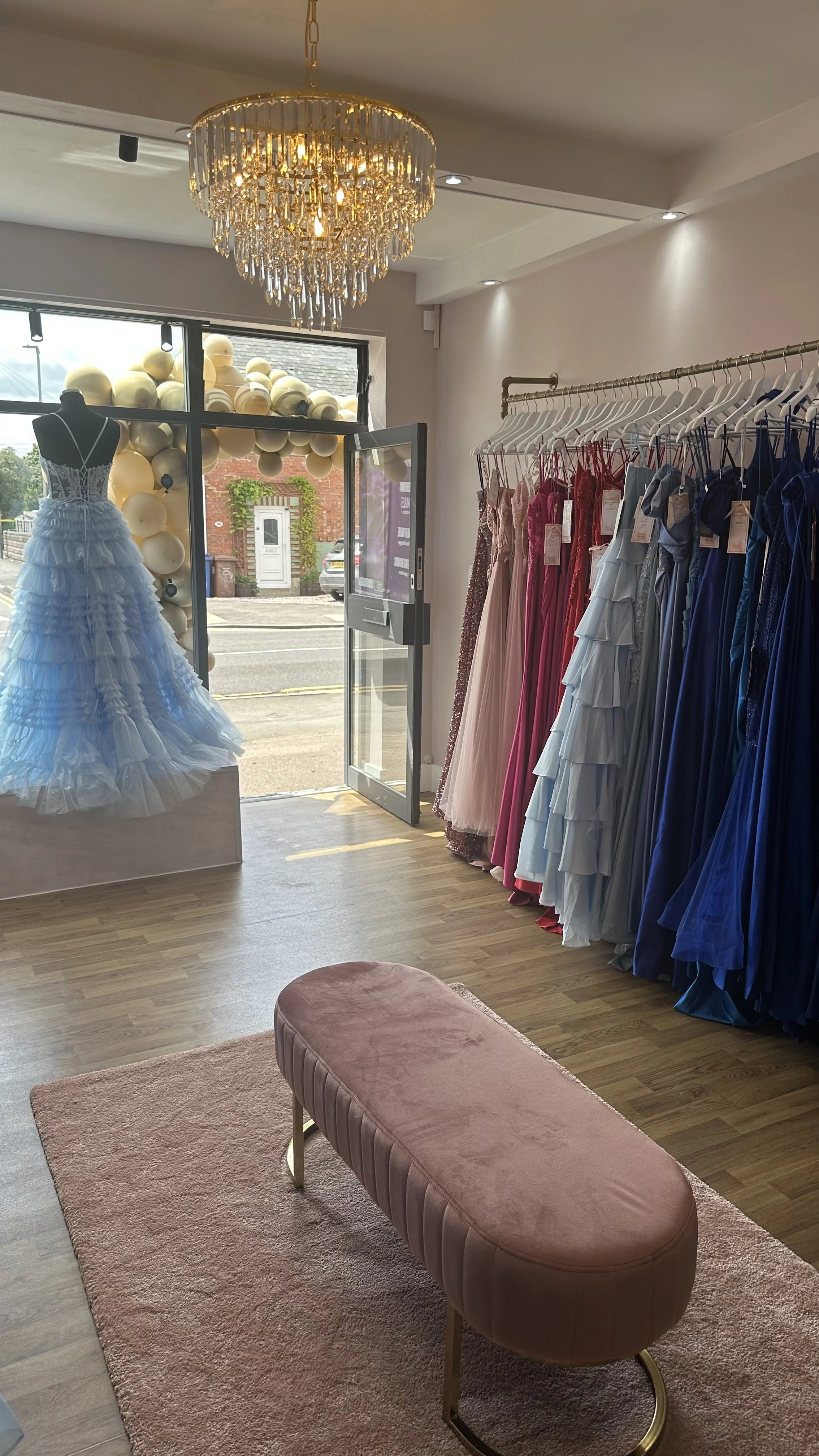 Inside Prom dress shop showing rail of prom dresses in blue, red, navy and blush tones