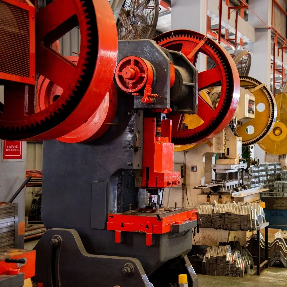 A large industrial machine with red and black gears in a factory setting.