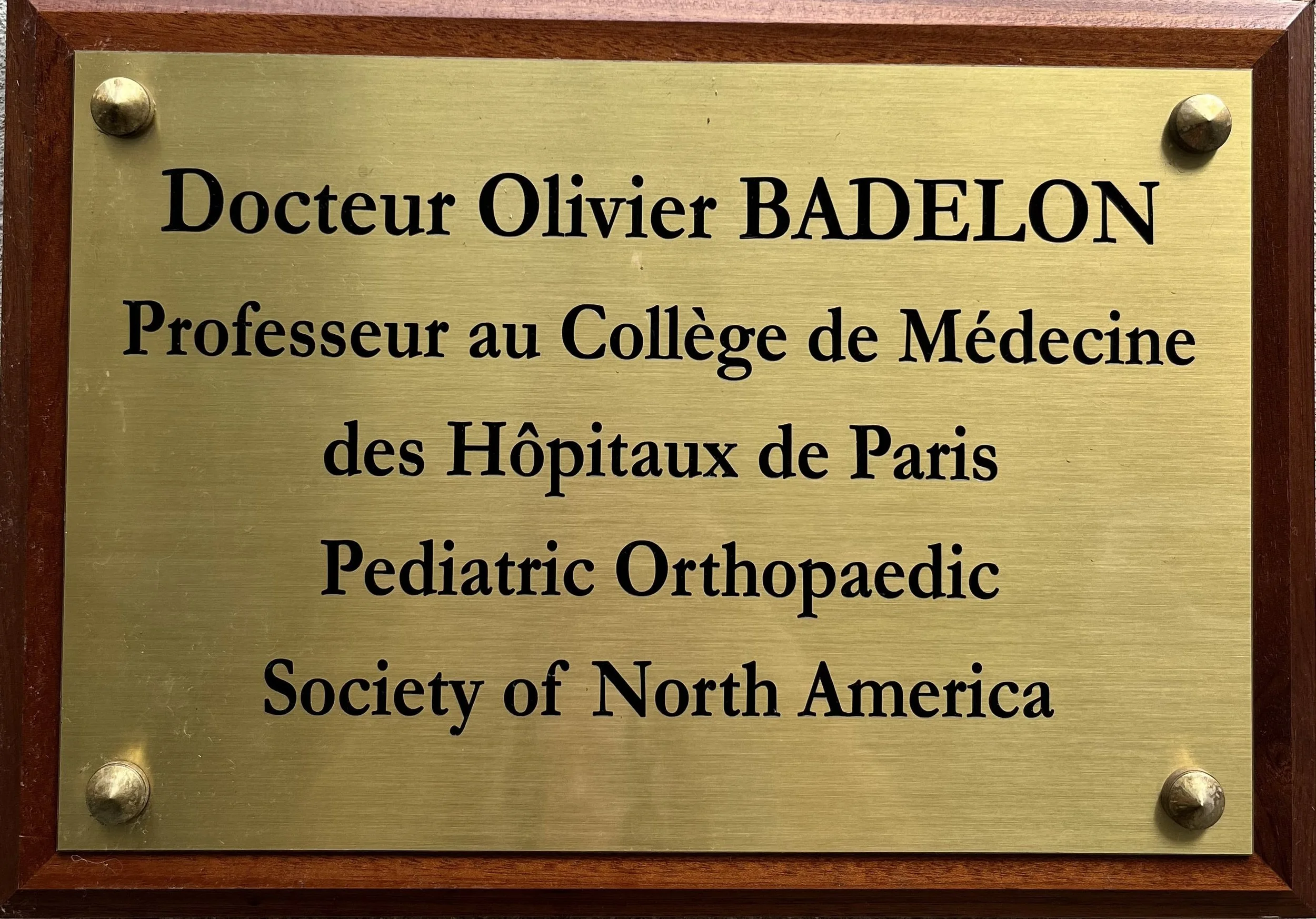Plaque professionnelle du Docteur Olivier Badelon, chirurgien orthopédiste pédiatrique en Ile de France et dans le Morbihan, à Neuilly sur Seine, à Vannes et indiquant qu'il est professeur au Collège de Médecine de la Société du Nord de l'Amérique.