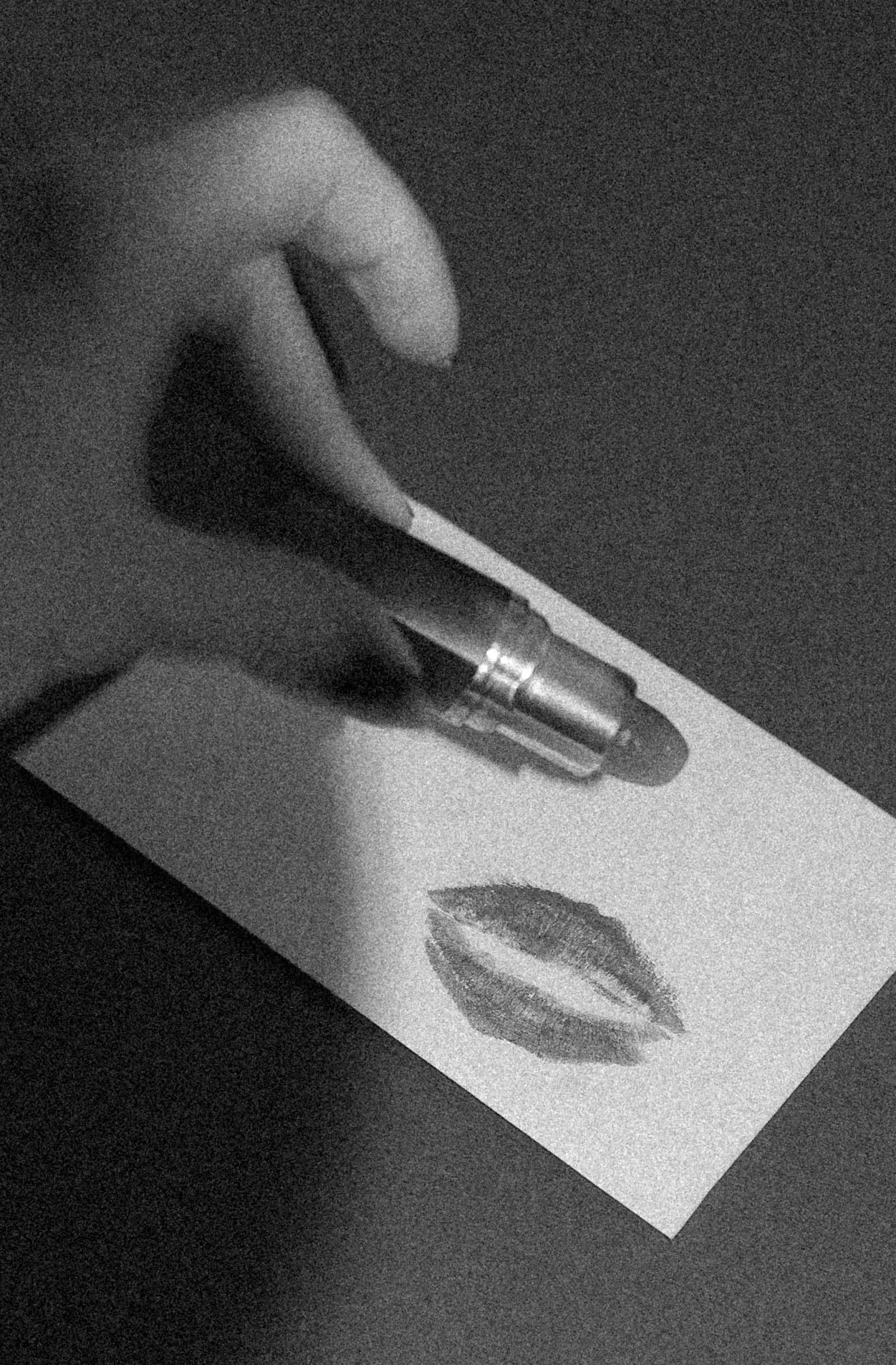 A hand writing beside a page marked with a lipstick kiss, from Love Between the Lines.