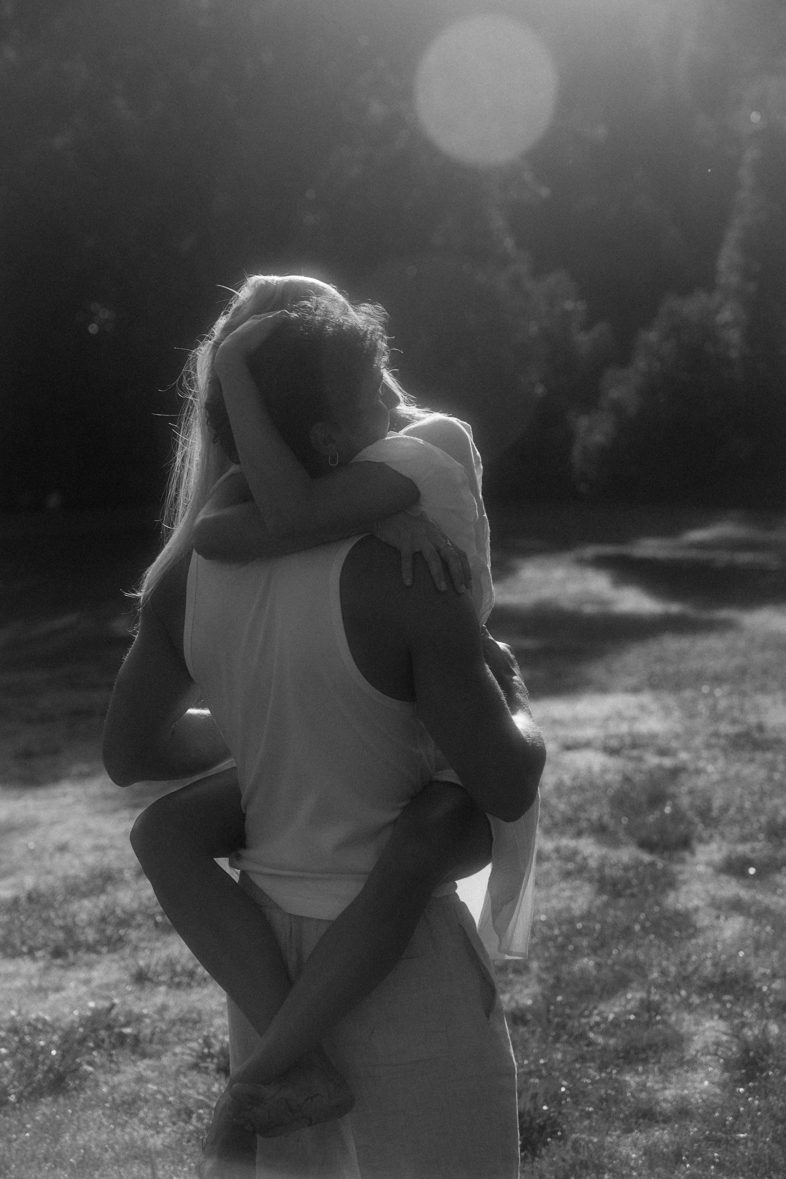 A couple at sunset, one carrying the other on their back, laughing together.