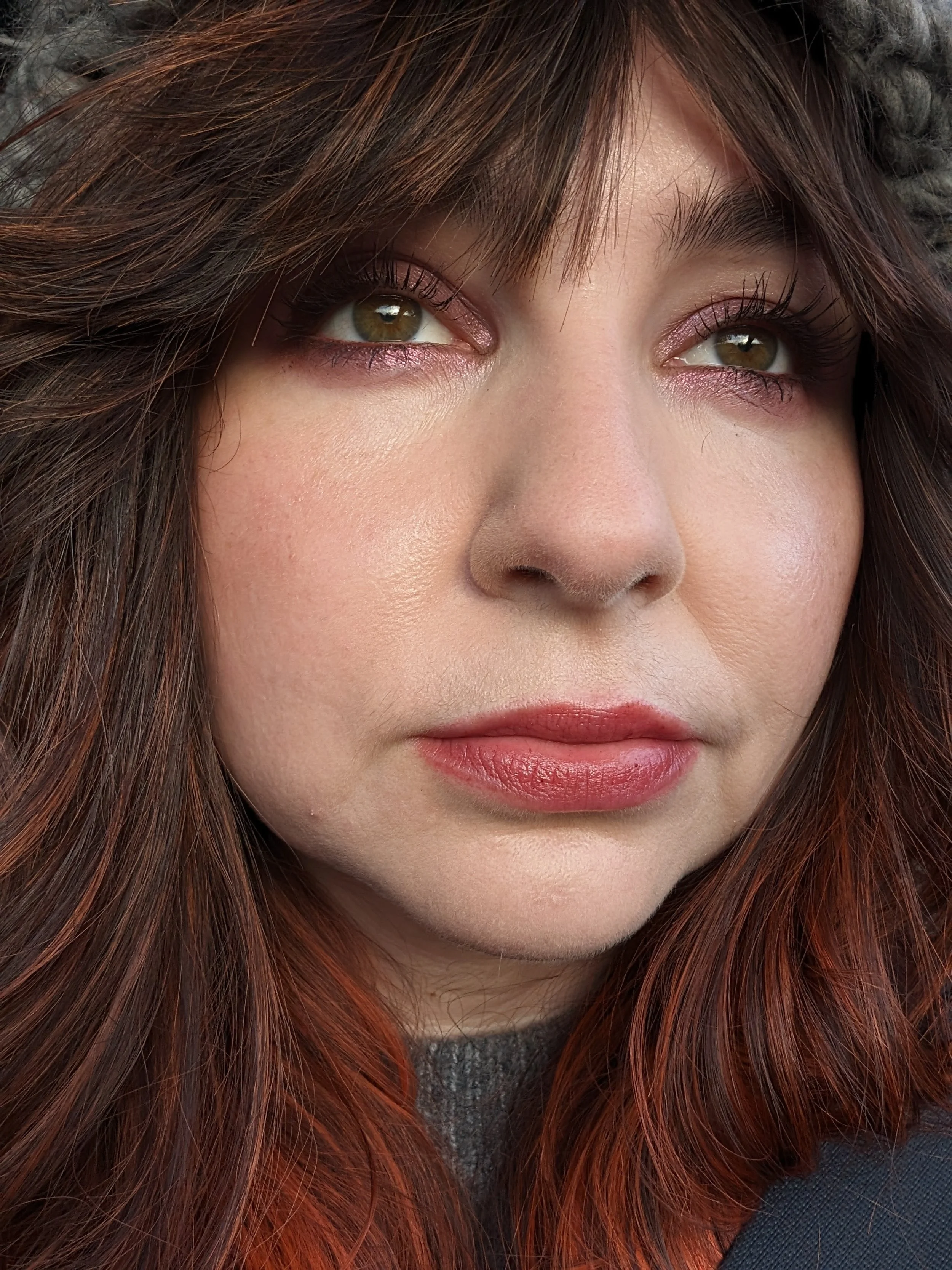 Close-up of a woman's face with brown hair, hazel eyes, and natural makeup.