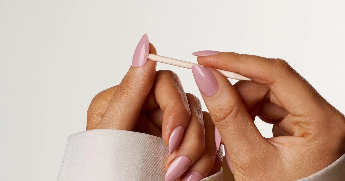 Hands holding a cotton swab against a plain background