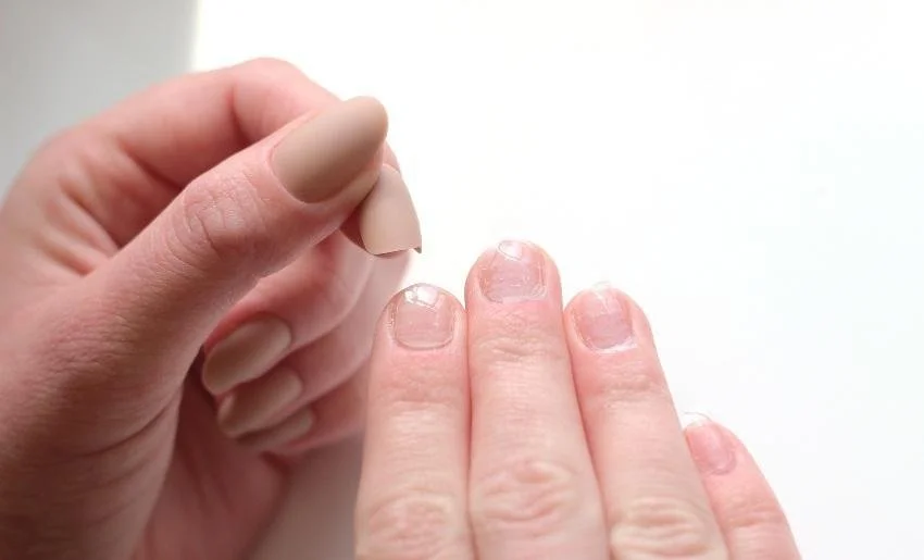 Close-up of a person applying clear nail polish to their fingernails.