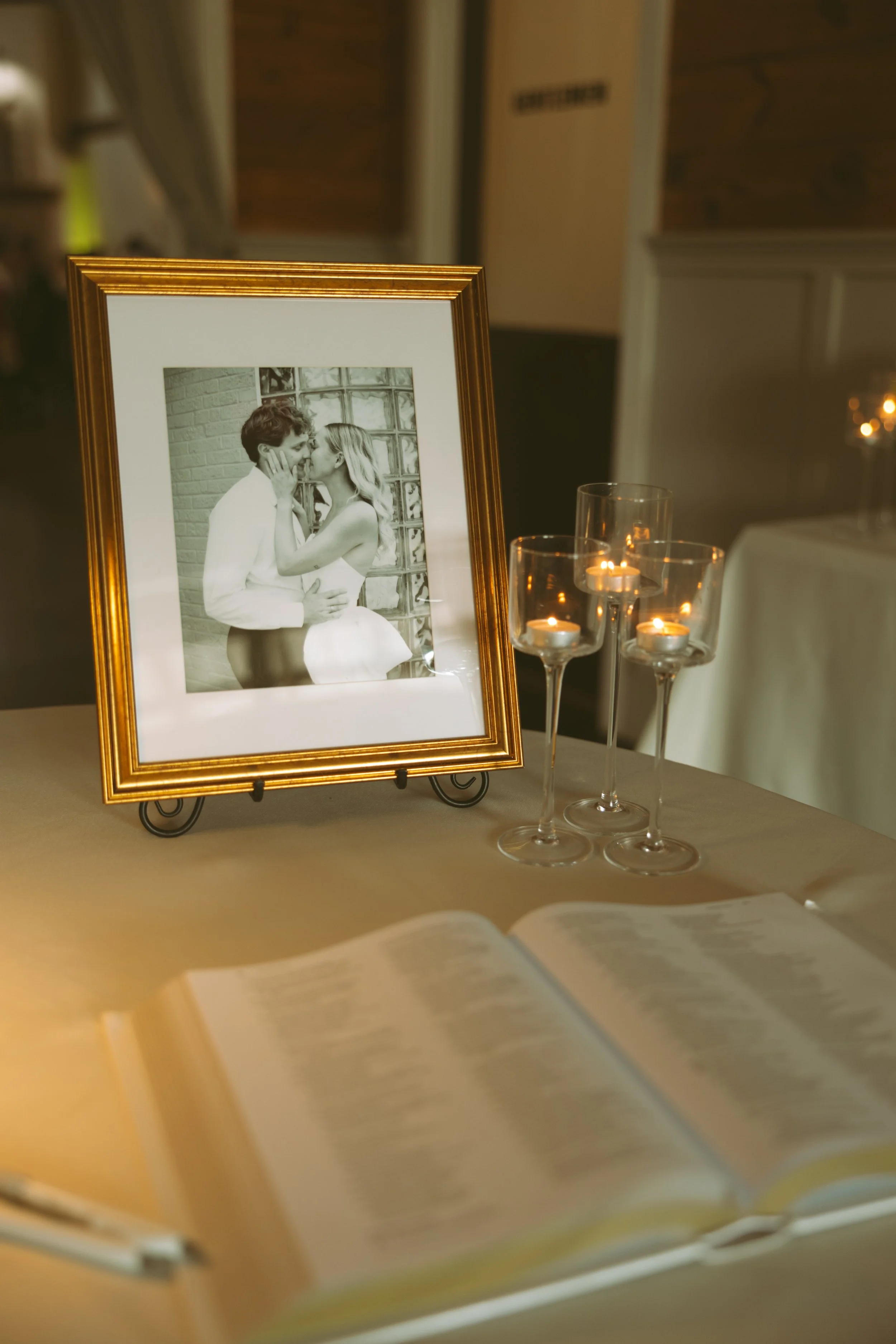 A framed black-and-white photograph of a couple sharing a kiss, displayed on a table with lit candles nearby.