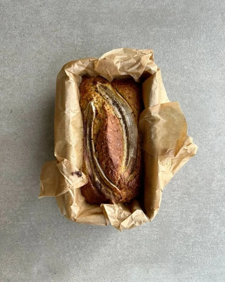 Geröstetes Fleisch mit einer Bananenpflanze in einem Backofen, eingepackt in braunem Papier.