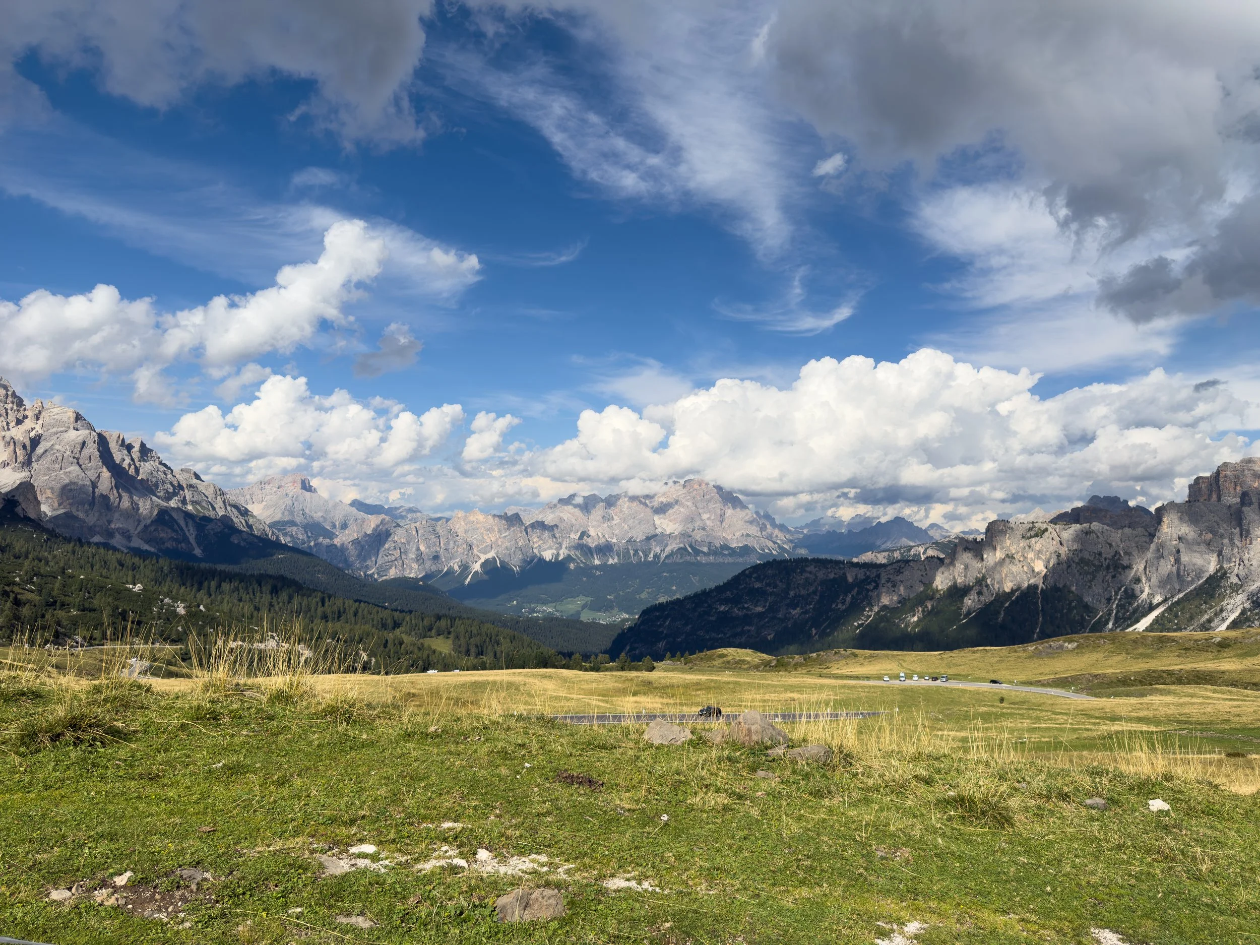 Alpine meadow and Dolomites peaks above a mountain pass road, Luxe Velo Dolomites tour