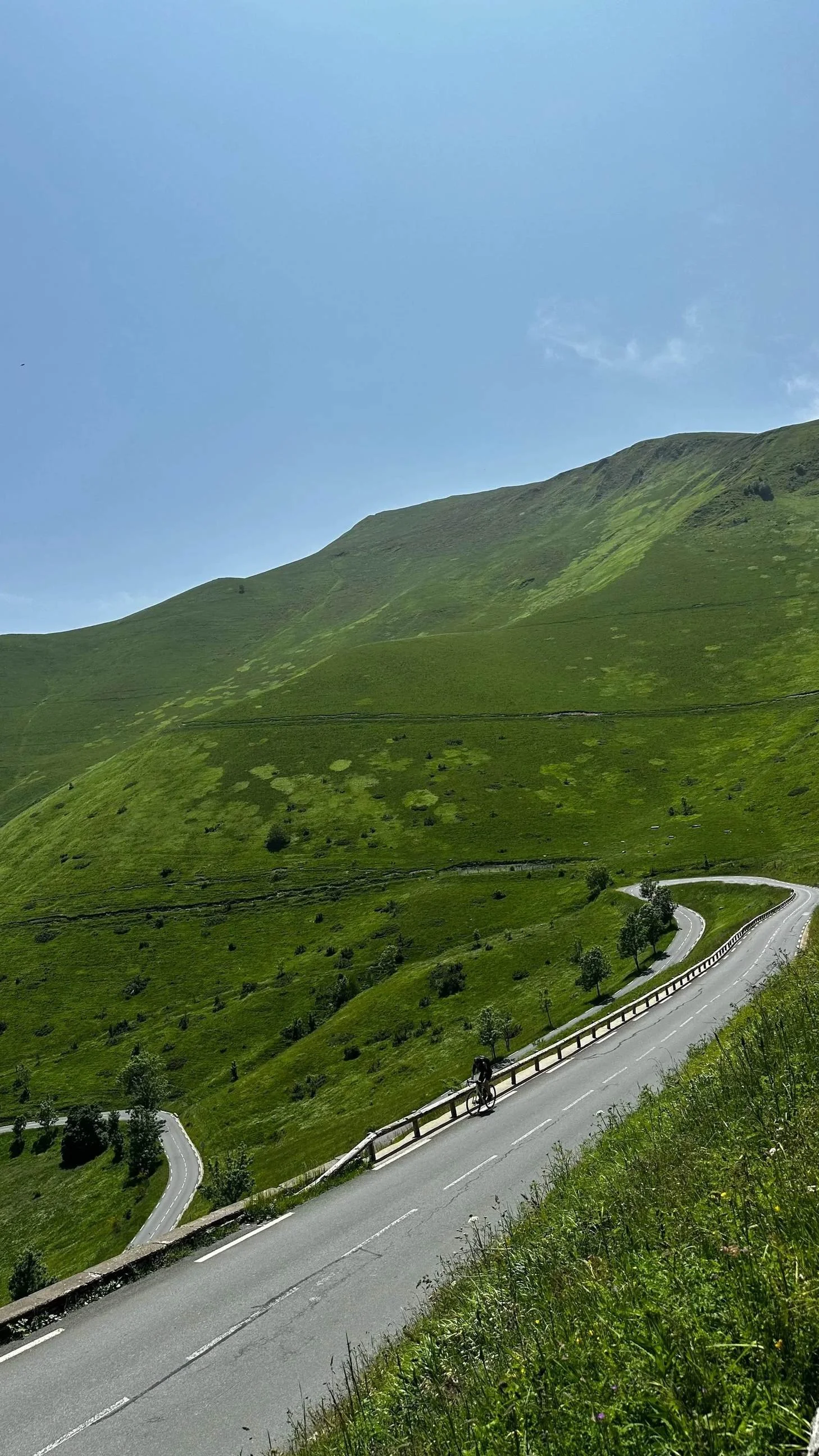 Road curving up green slopes of the Col de Peyresourde on the Luxe Velo Pyrenees cycling tour