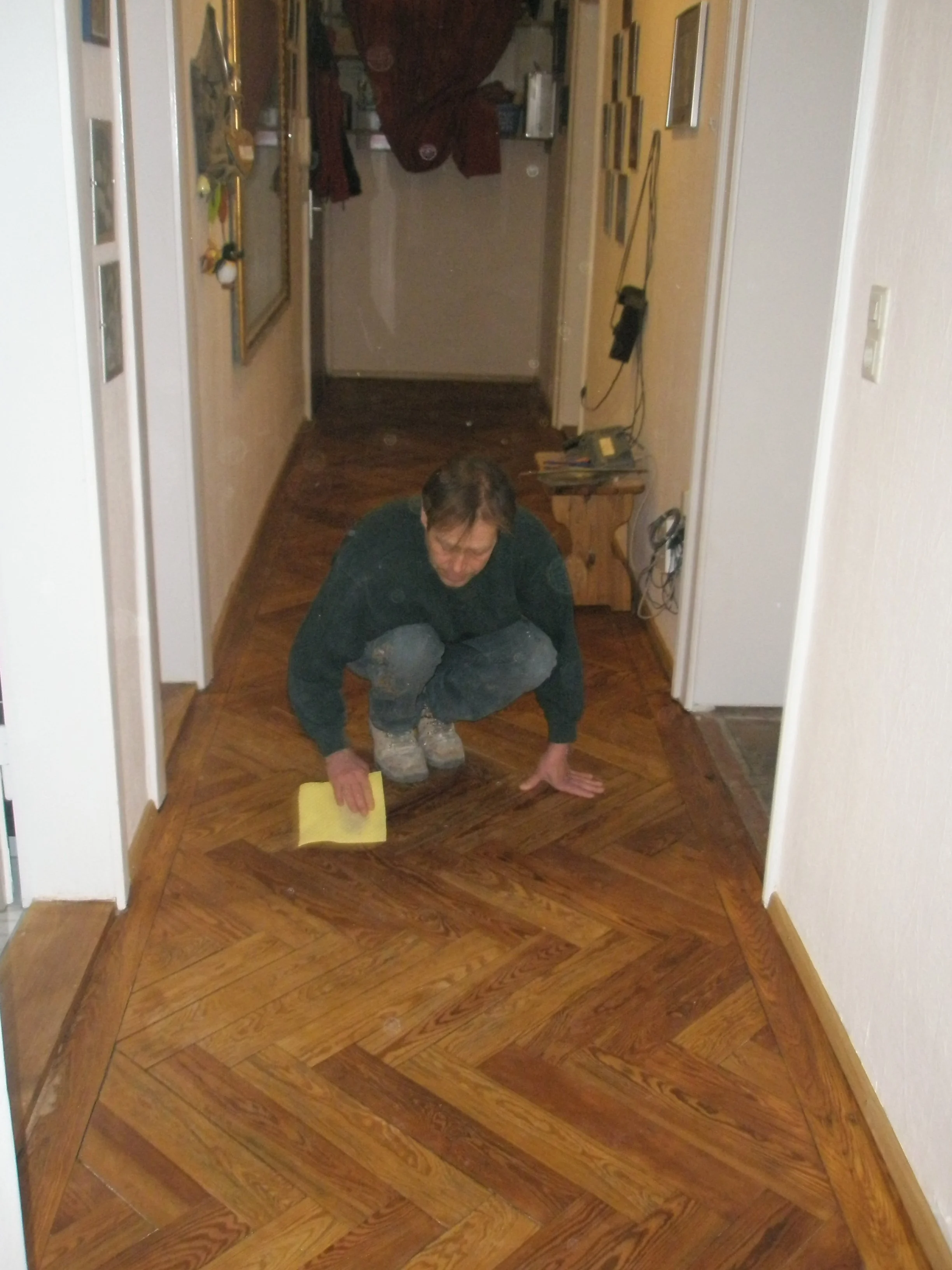Mann, der auf einem Holzboden ein kleines Reinigungsgerät benutzt.