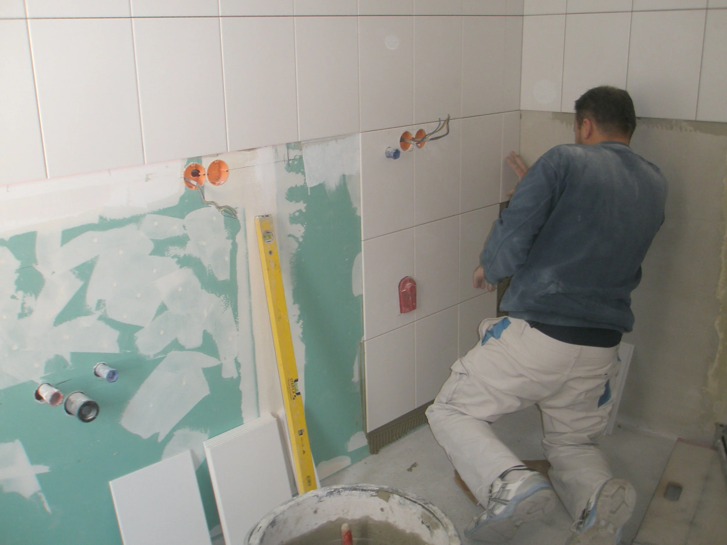 Handwerker, der Fliesen in einer Küche oder Bad verfugt.