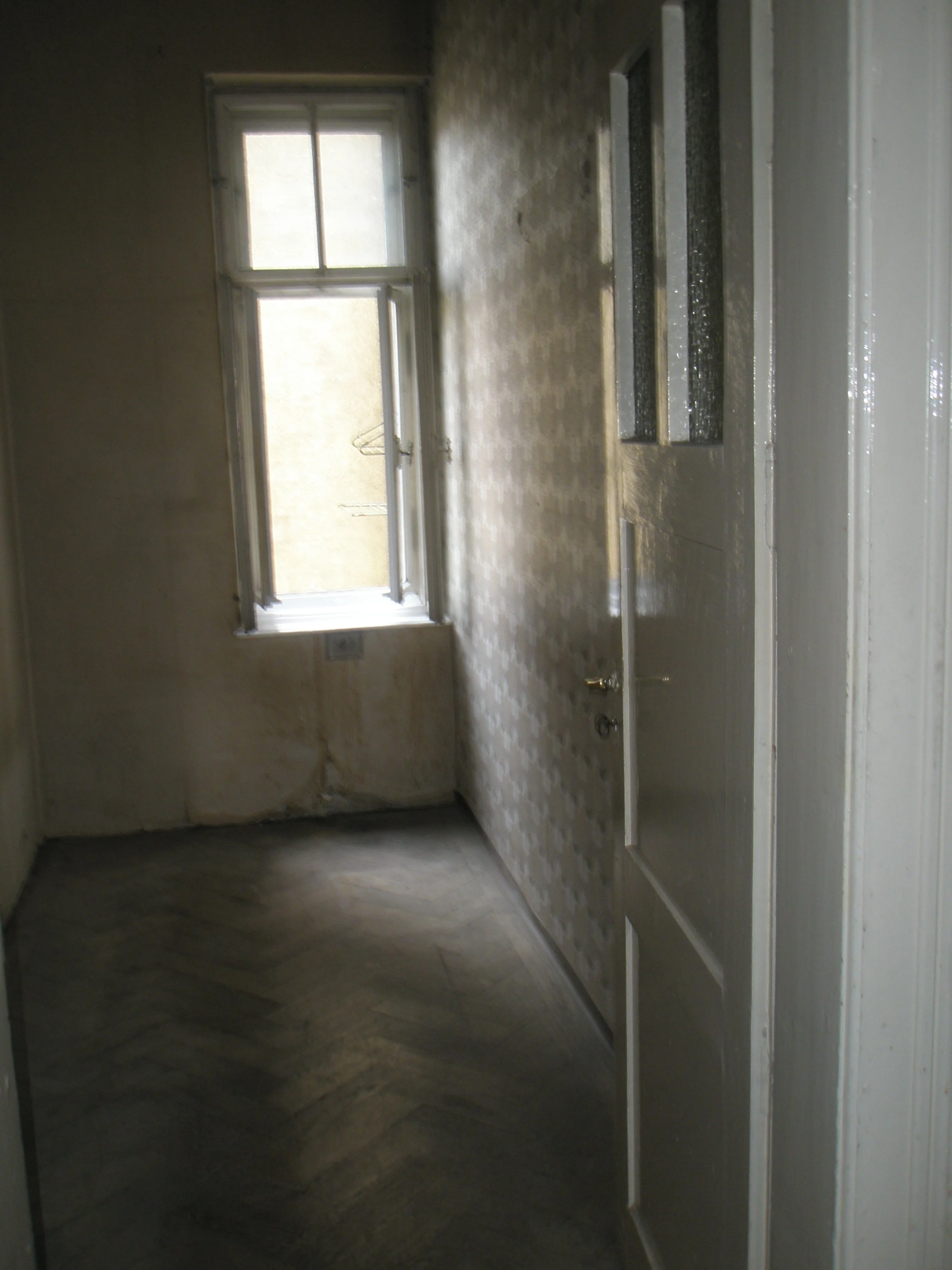 Leeres Raum mit großen Fenstern und einer Klinkerwand, wahrscheinlich eine noch nicht fertiggestellte Küche oder Raum in einem Gebäude.