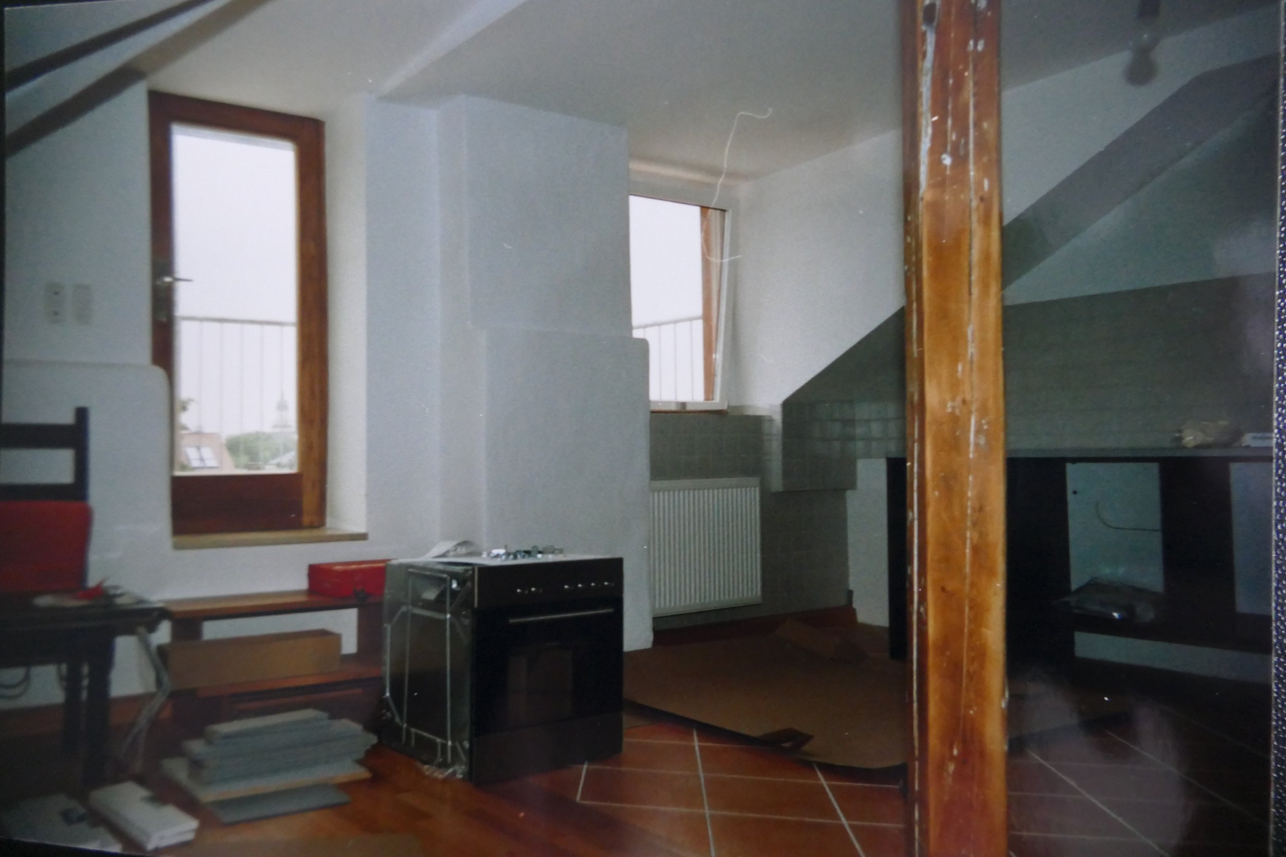Innenraum eines Hauses unter Renovierung mit Fenstern, Heizkörper, Küchenutensilien und Holzarbeiten.