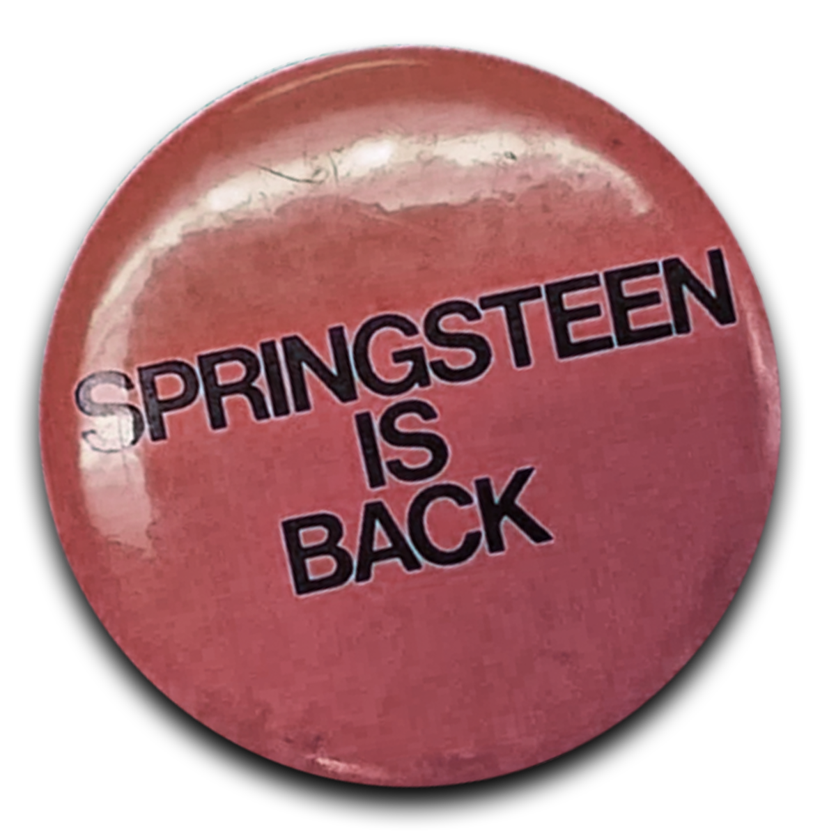 Pink button or badge with black text that says "Springsteen is Back".