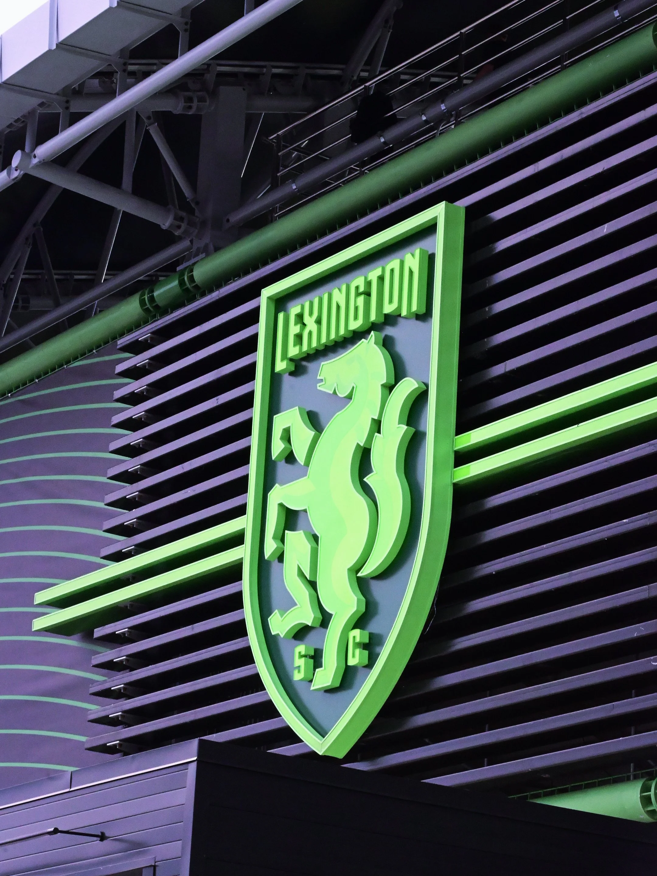 Close-up of a neon green illuminated sign with the words 'LEXINGTON ' on a modern building exterior with black horizontal slats.