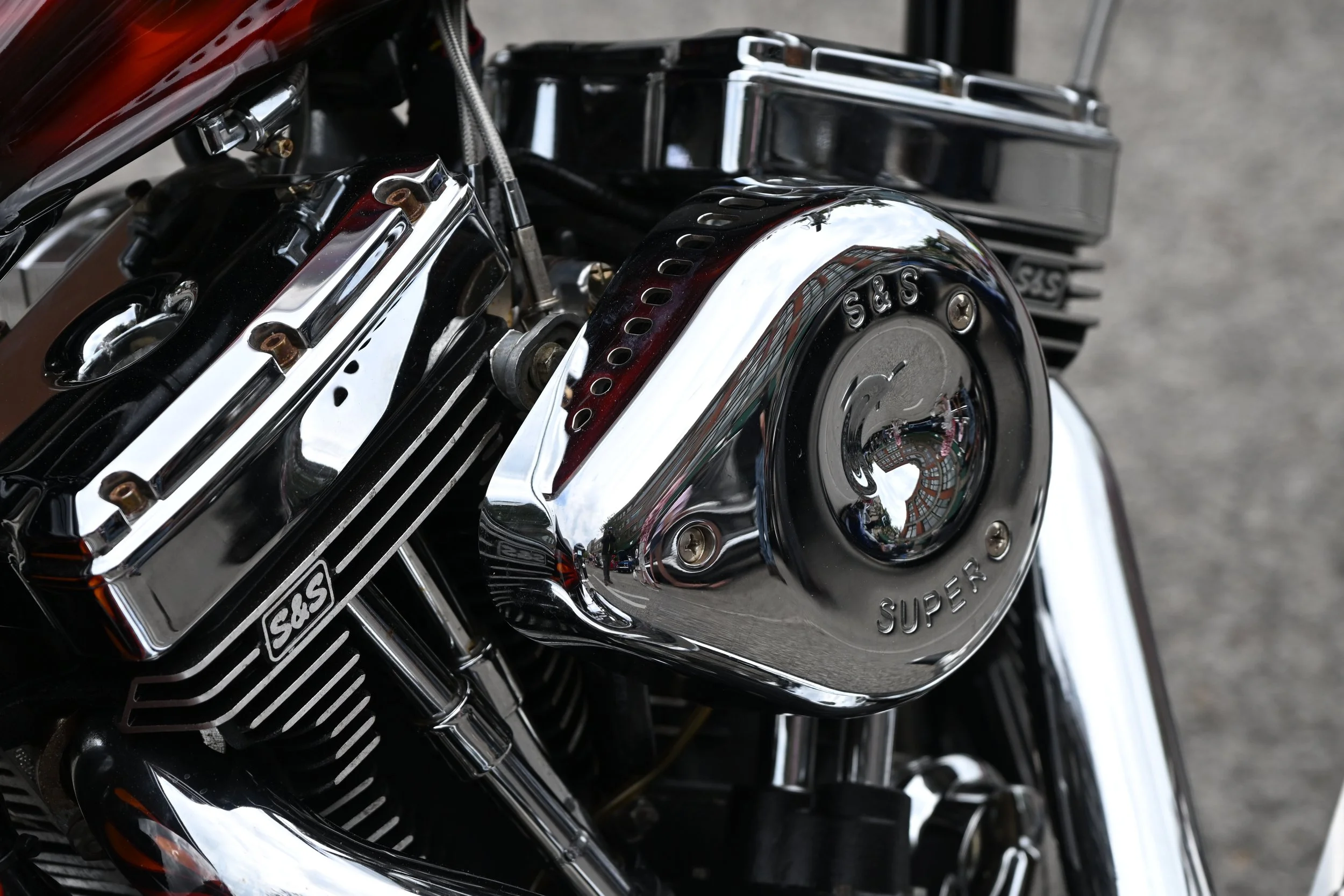 Close-up of a motorcycle engine with chrome and black parts, including S&S Super logo on a chrome cover.