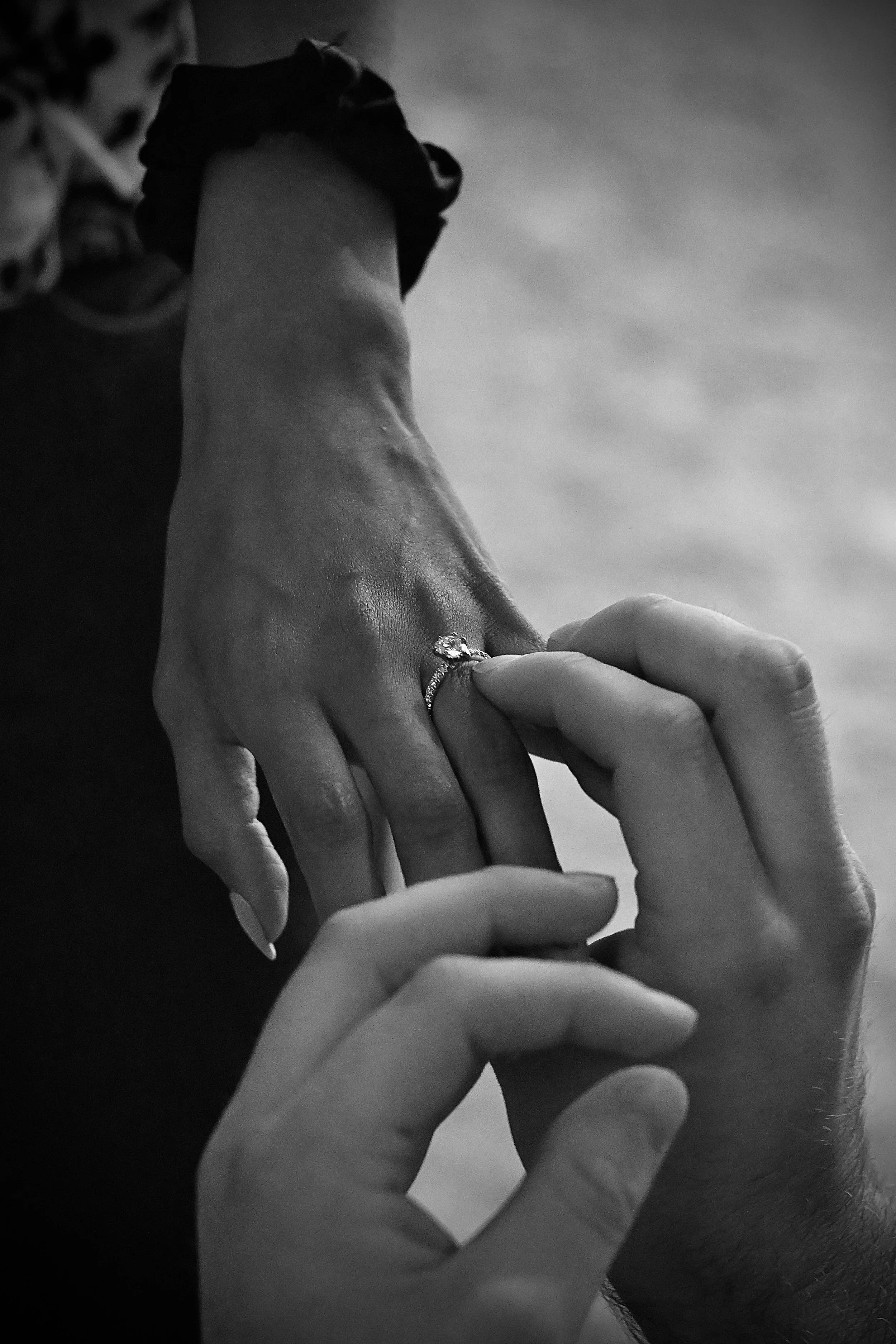 Two hands embracing while an Engagement ring is slipped on promising forever.