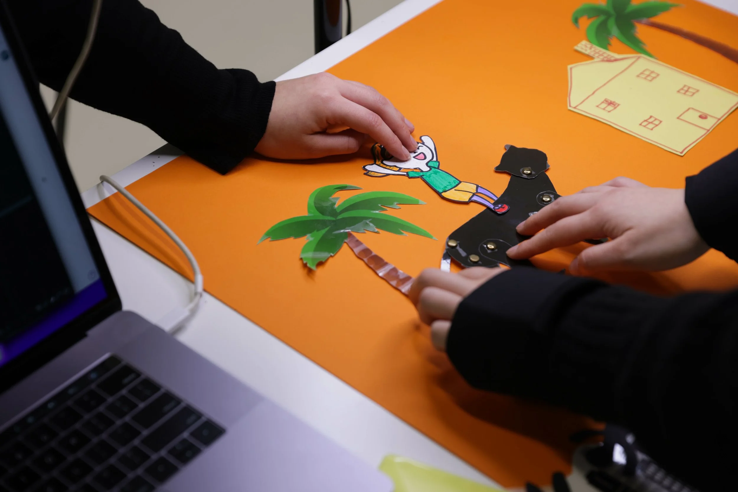 Paper cutout characters layed out on orange background