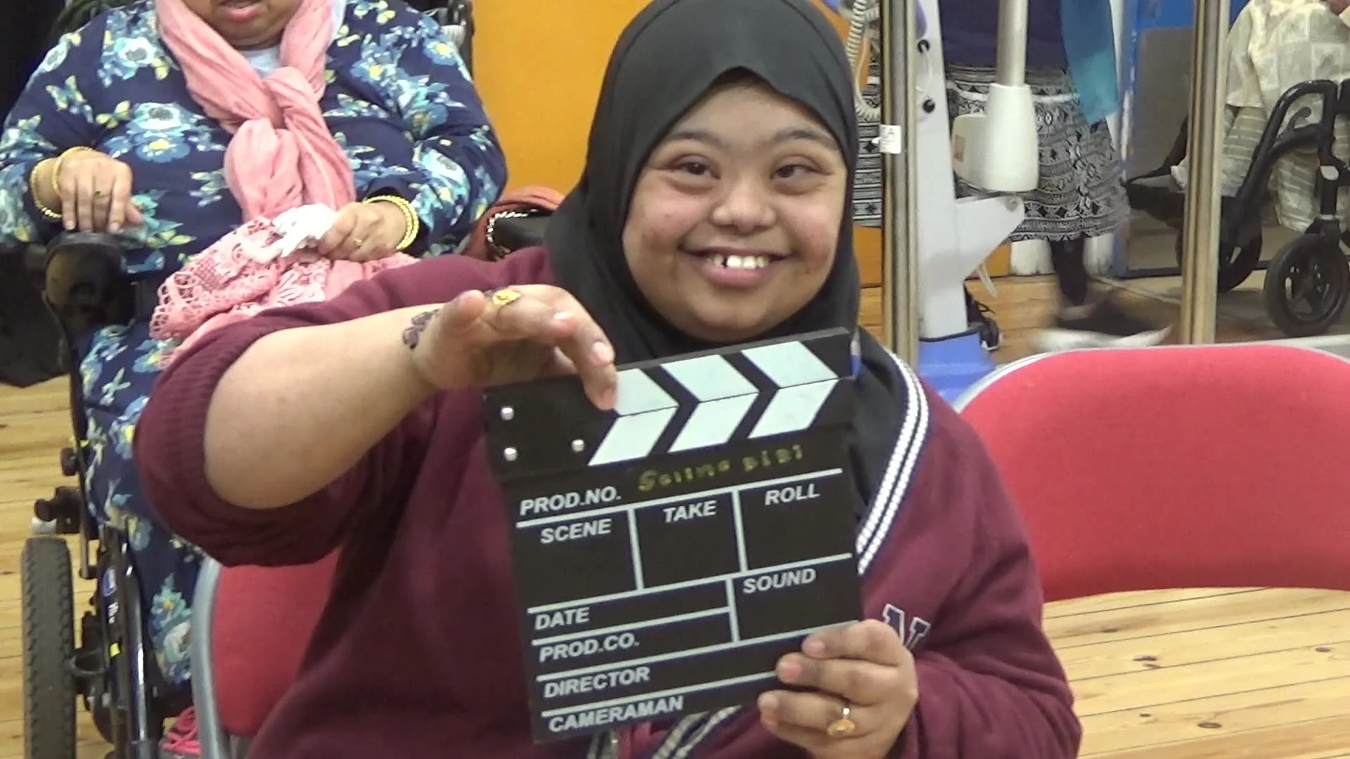 Smiling woman in wearing a hijab uses a movie clapper