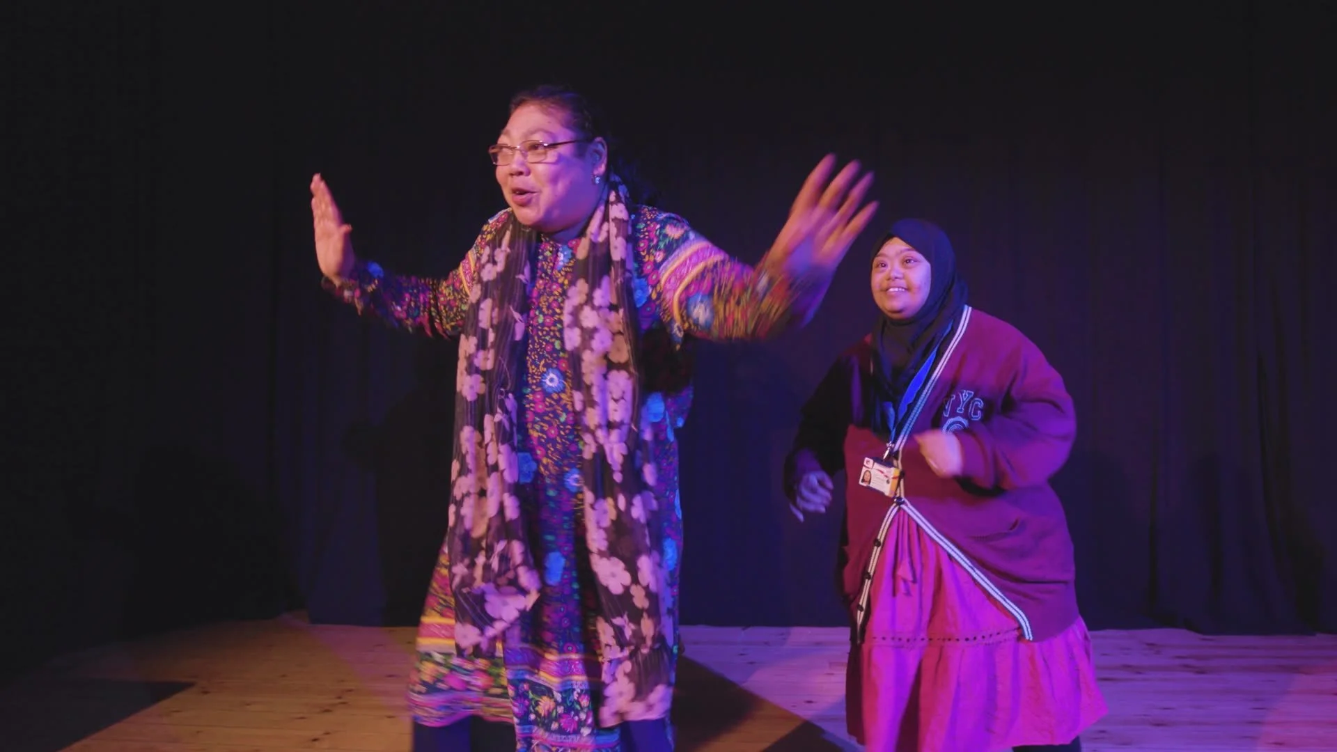 Two women dancing in purple light