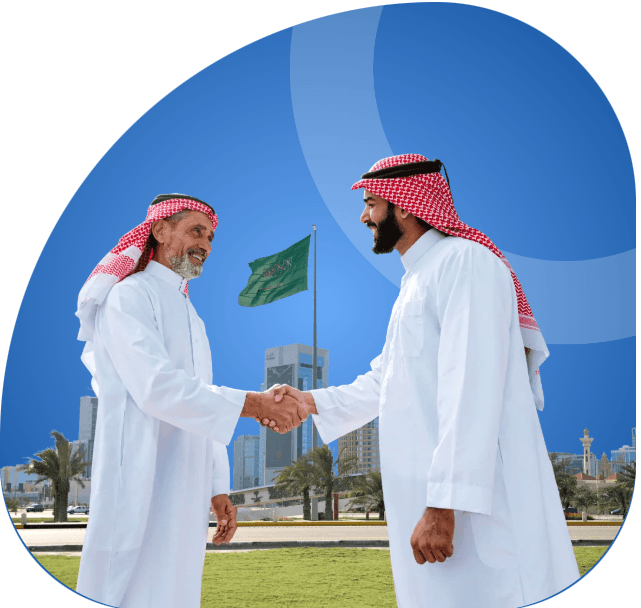 Two men in traditional Middle Eastern attire shaking hands in a city park with palm trees and modern buildings, with a flag and a blue sky in the background.