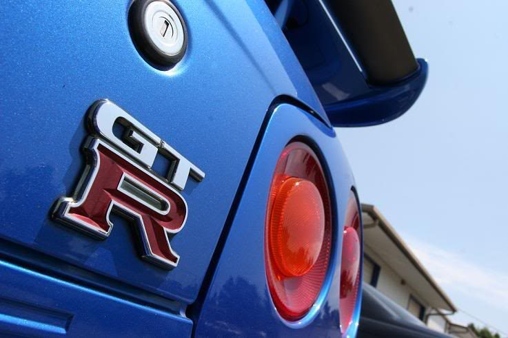 Close-up of a blue Nissan GT-R car's rear, showing the GT-R badge and round red taillights.