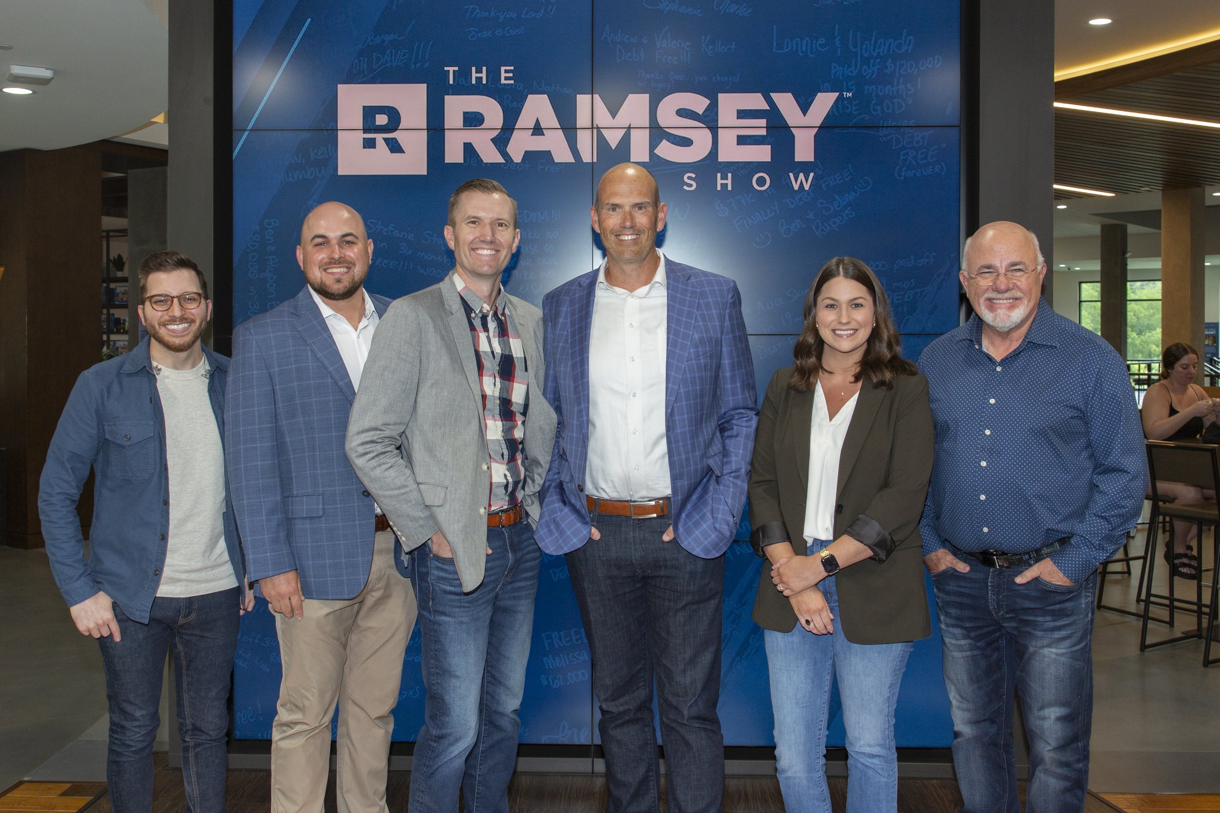 The Smartvestor Pros of Steward Wealth Strategies standing in front of "The Ramsey Show" sign at Ramsey Solutions in Brentwood, TN. From left to Right: George Kamel, Graham Burke, Dennis Bohm, Brant Spesshardt, Amy Welborn, Dave Ramsey